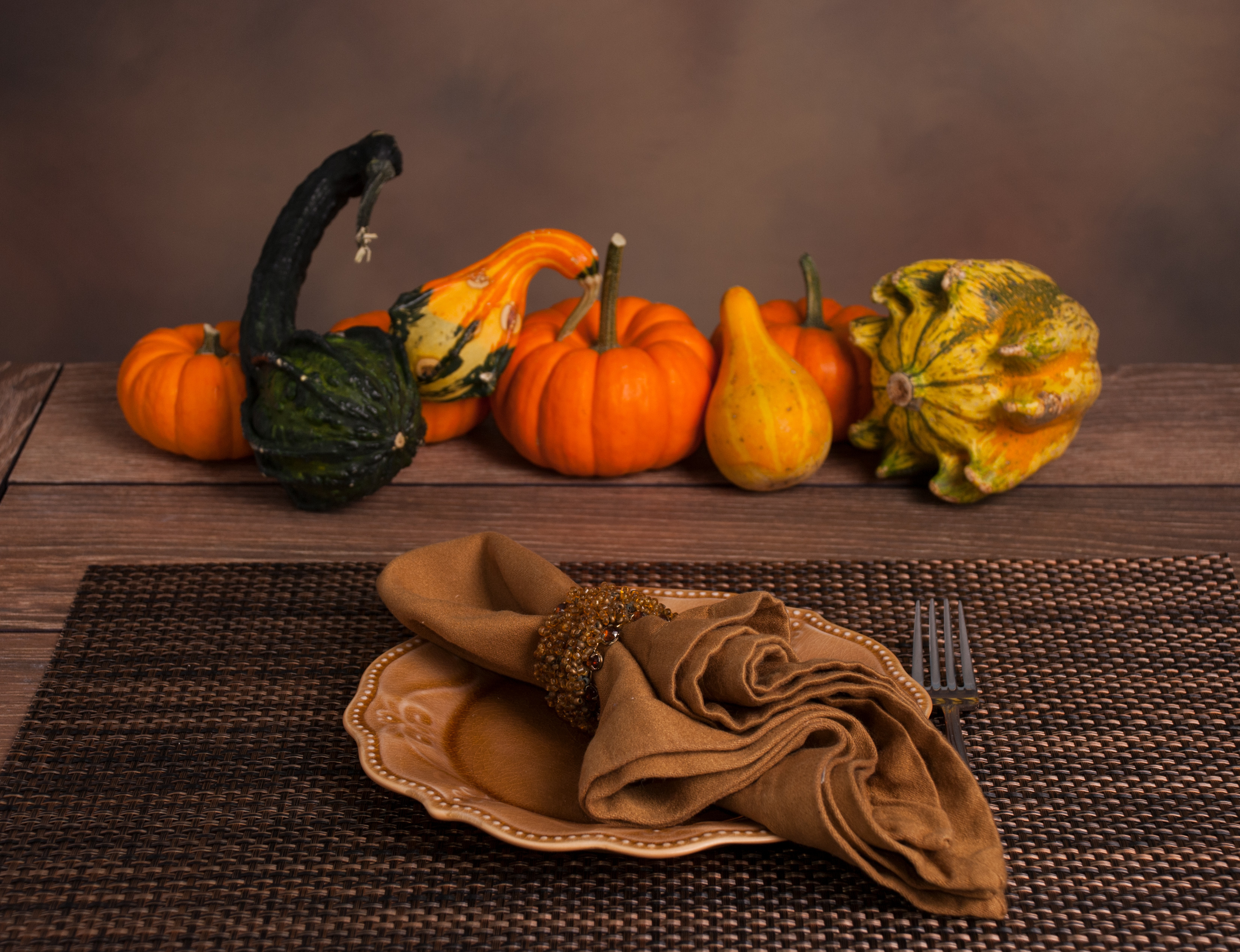 Assortment of gourds on a holiday table with a plate and napkin.