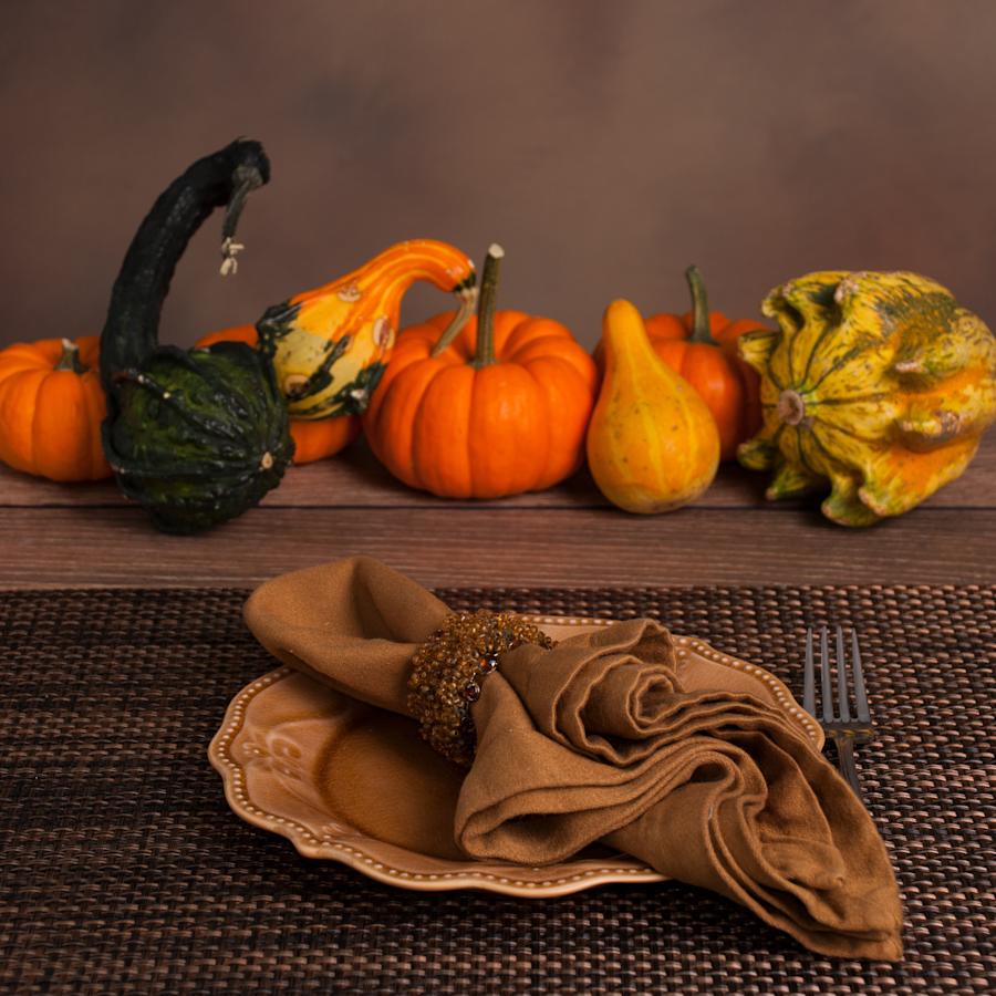 Assortment of gourds on a holiday table with a plate and napkin.
