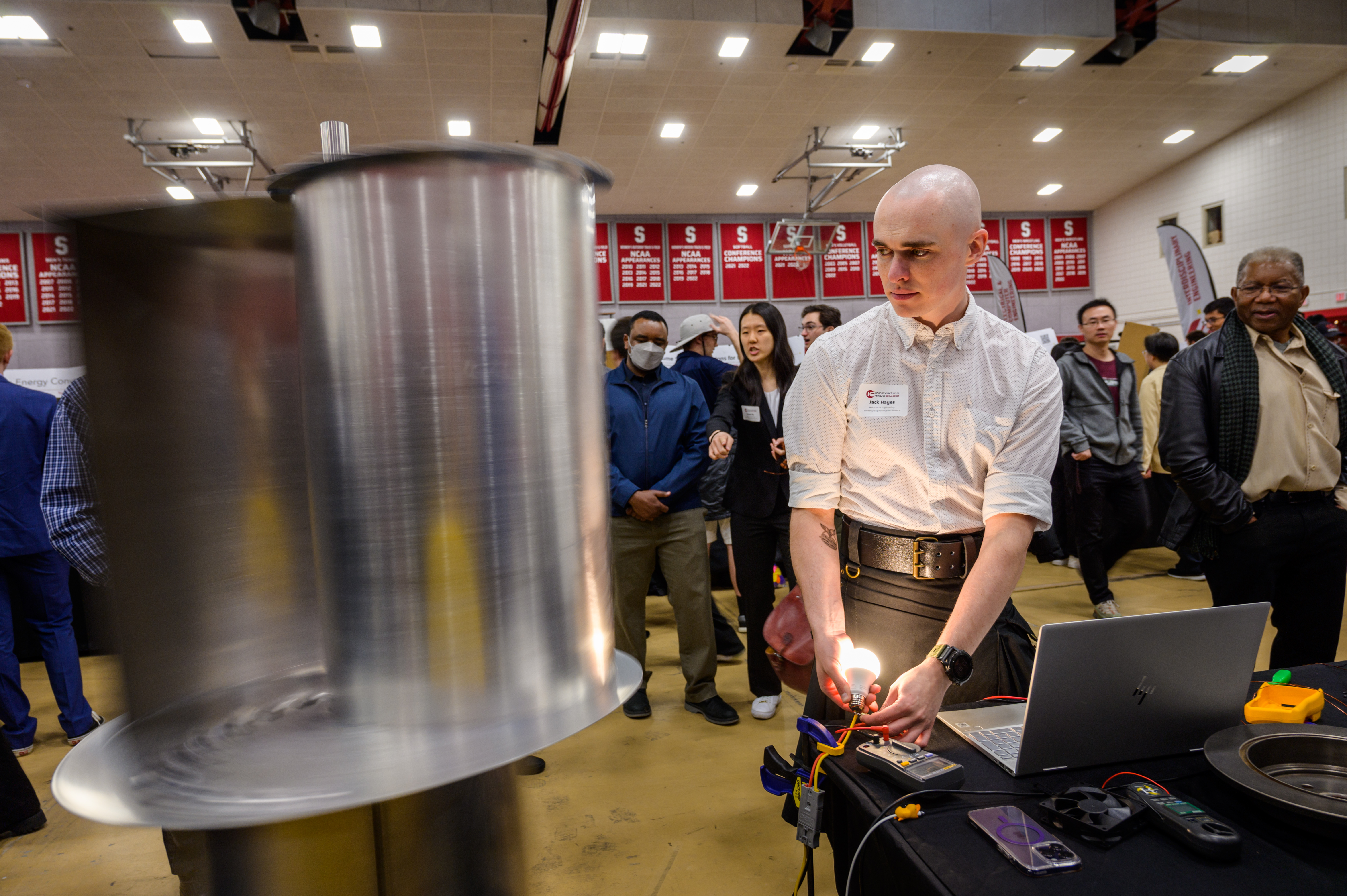 Student demonstrates his senior capstone project involving a metallic cylinder at Innovation Expo 2023 at Stevens.