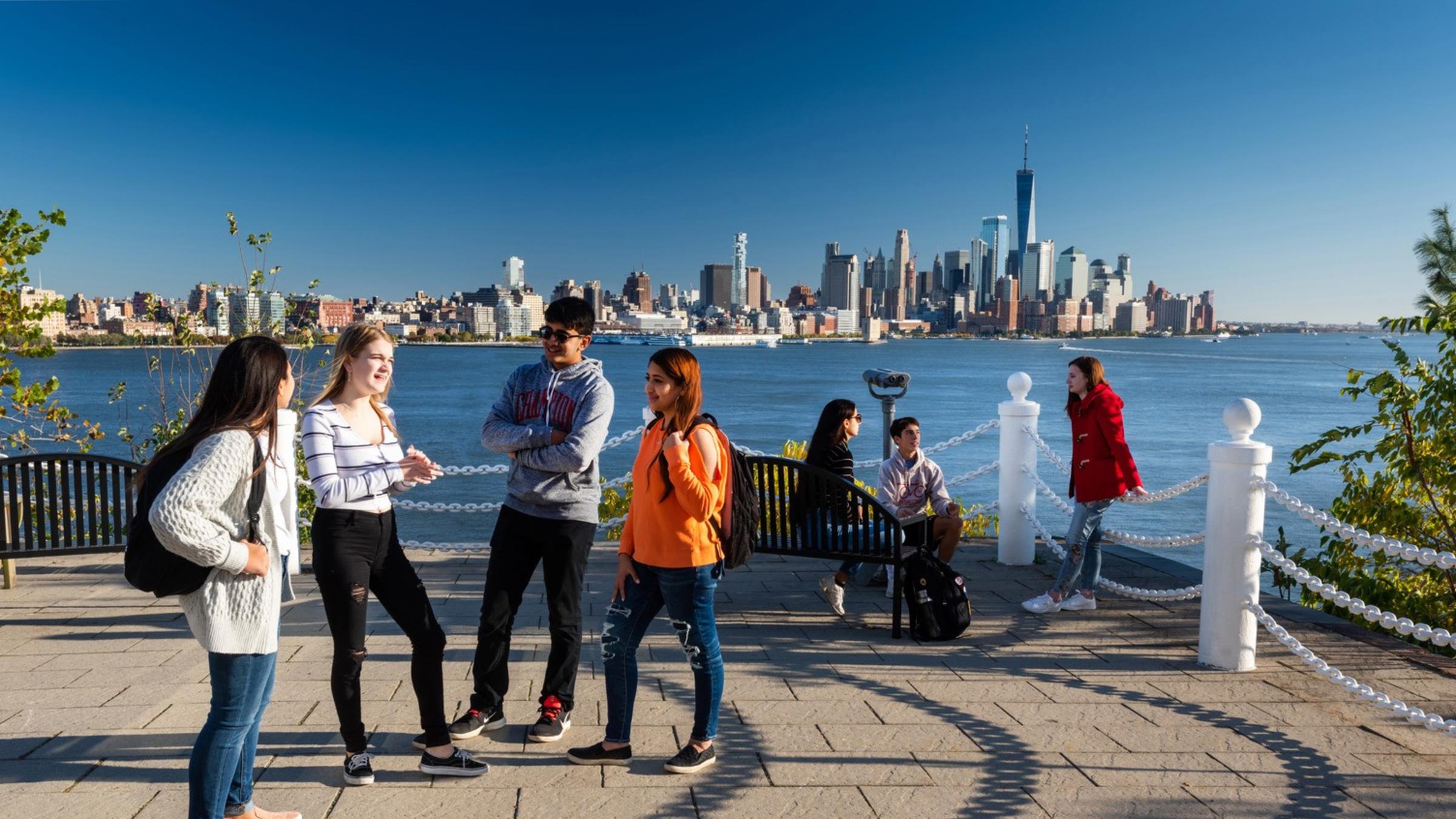 four students standing in a semicircle smiling at one another