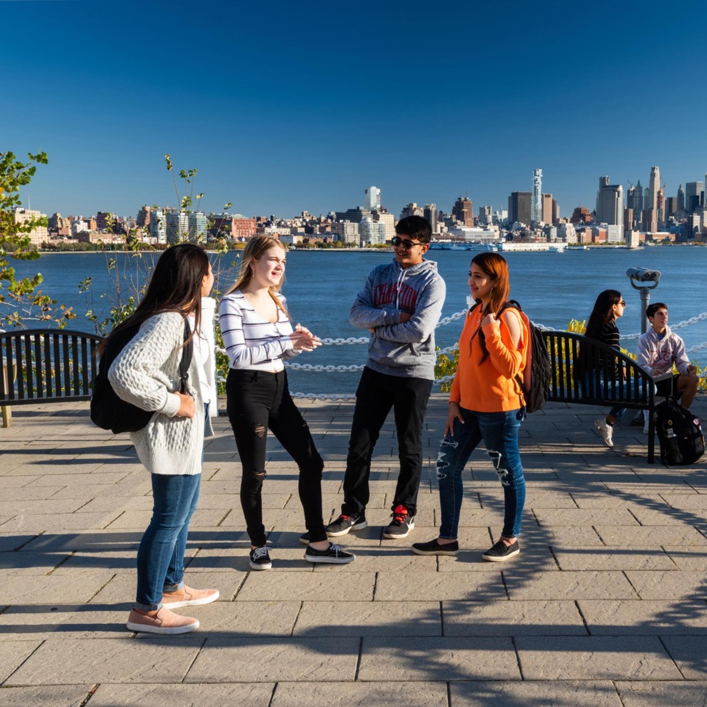 four students standing in a semicircle smiling at one another