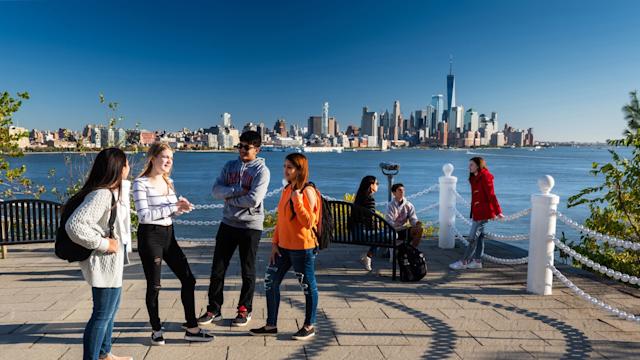 four students standing in a semicircle smiling at one another