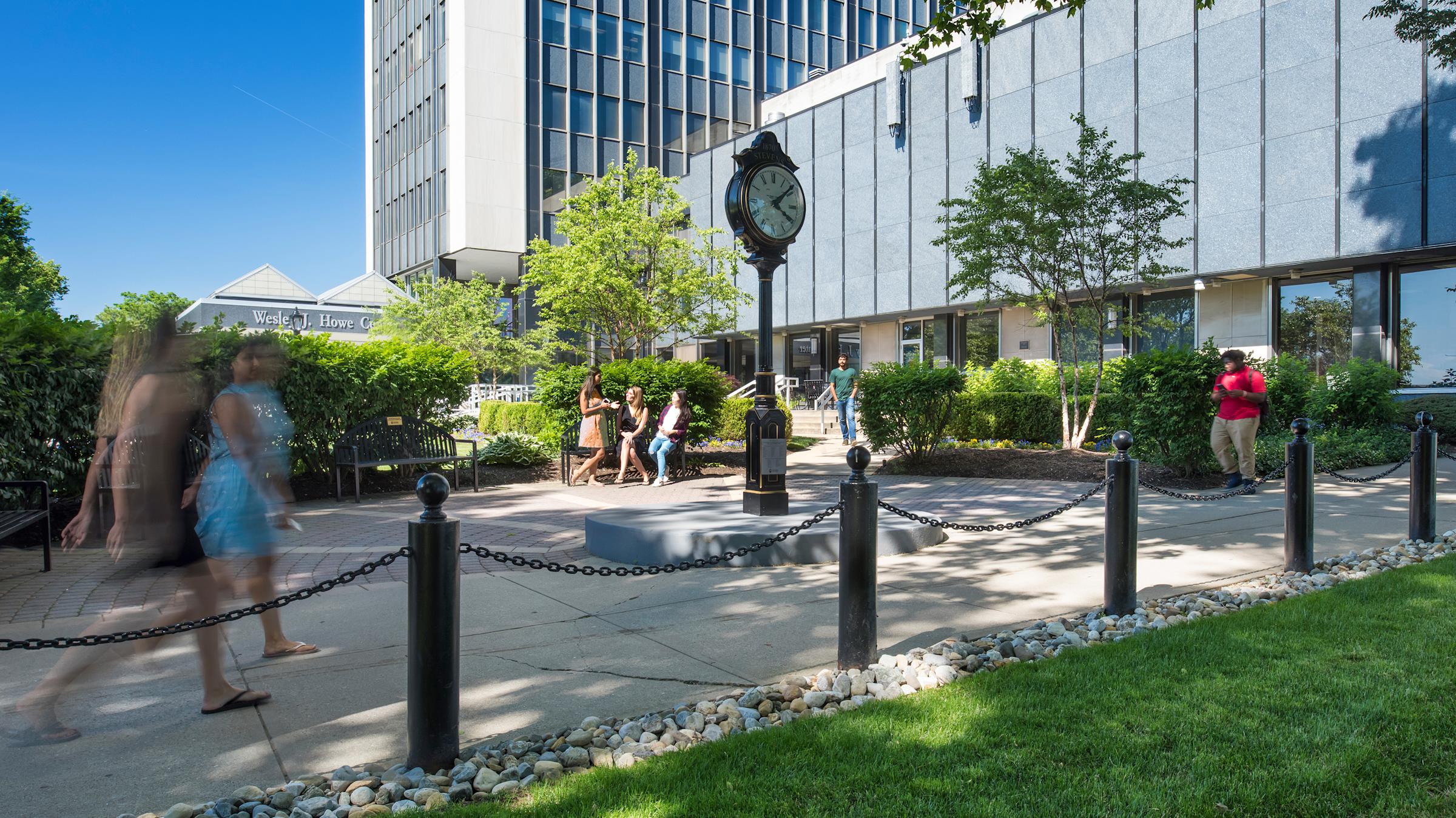 Stevens students walking on campus in front of clock.