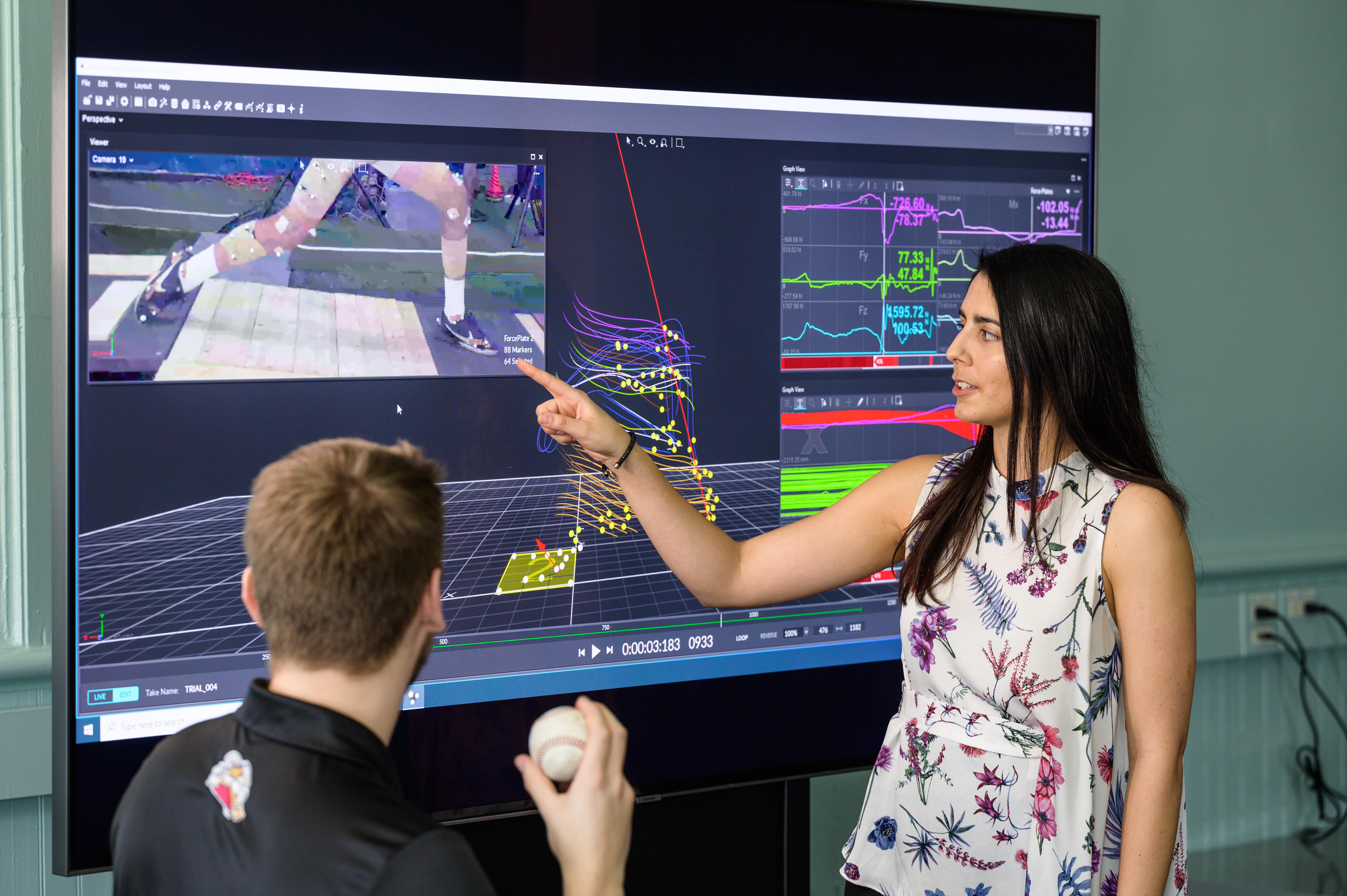Instructor in front of monitor guides model outfitted in motion capture technology.