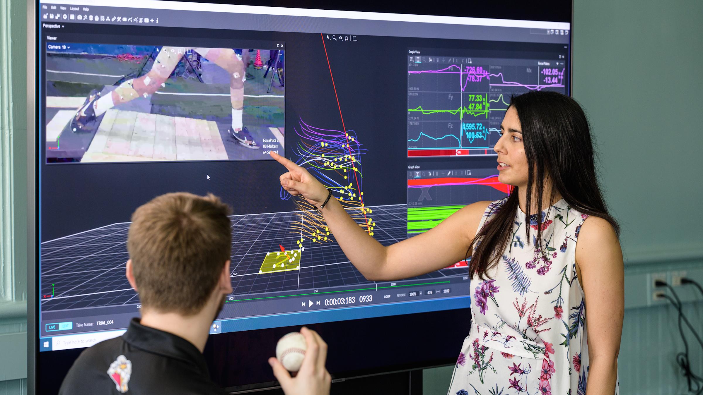 Instructor in front of monitor guides model outfitted in motion capture technology.