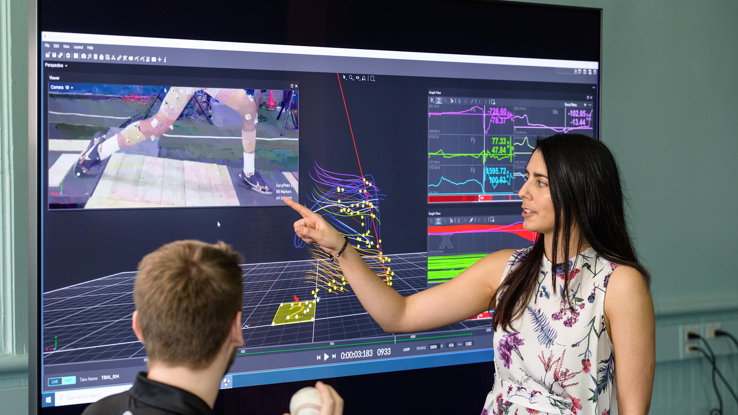 Instructor in front of monitor guides model outfitted in motion capture technology.