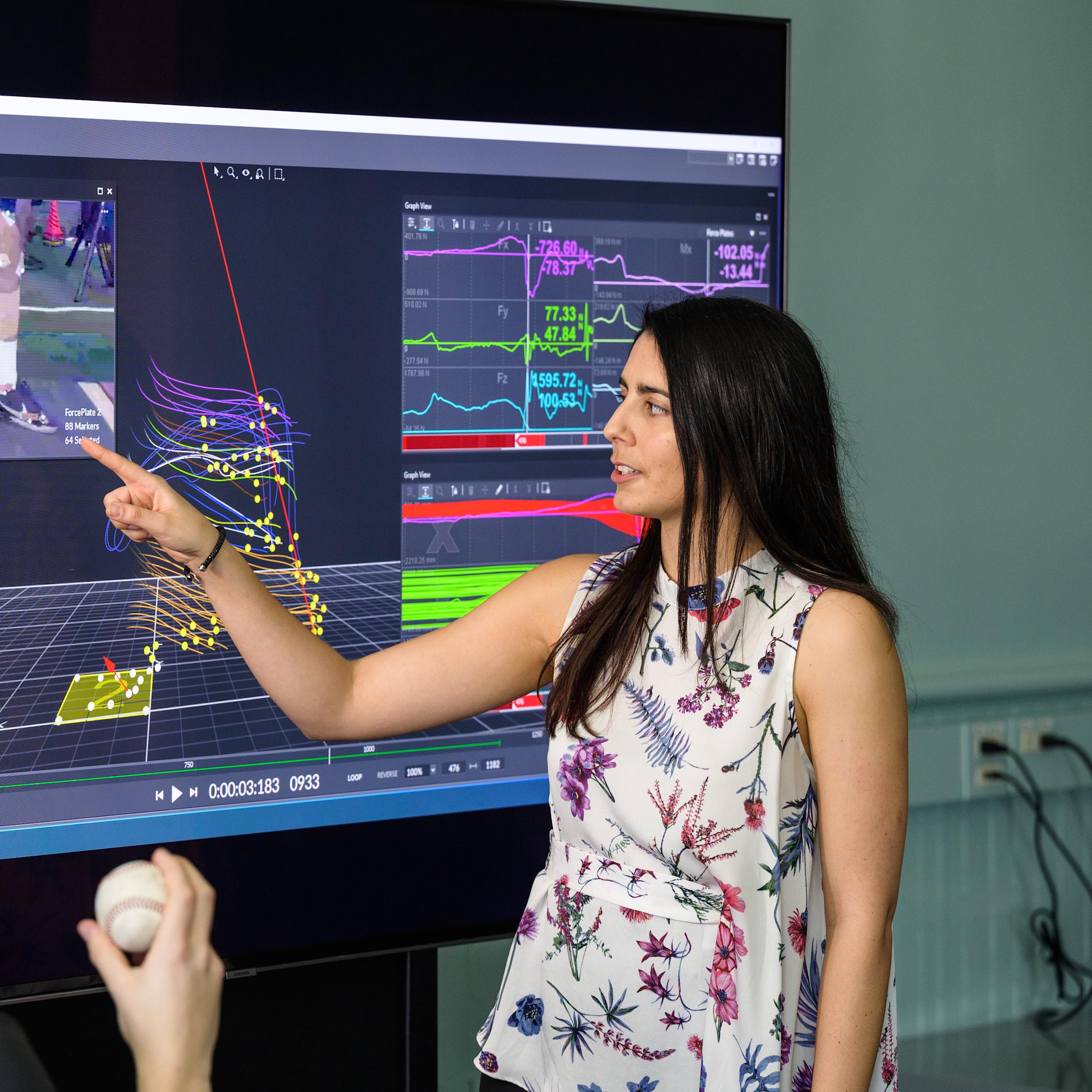 Instructor in front of monitor guides model outfitted in motion capture technology.
