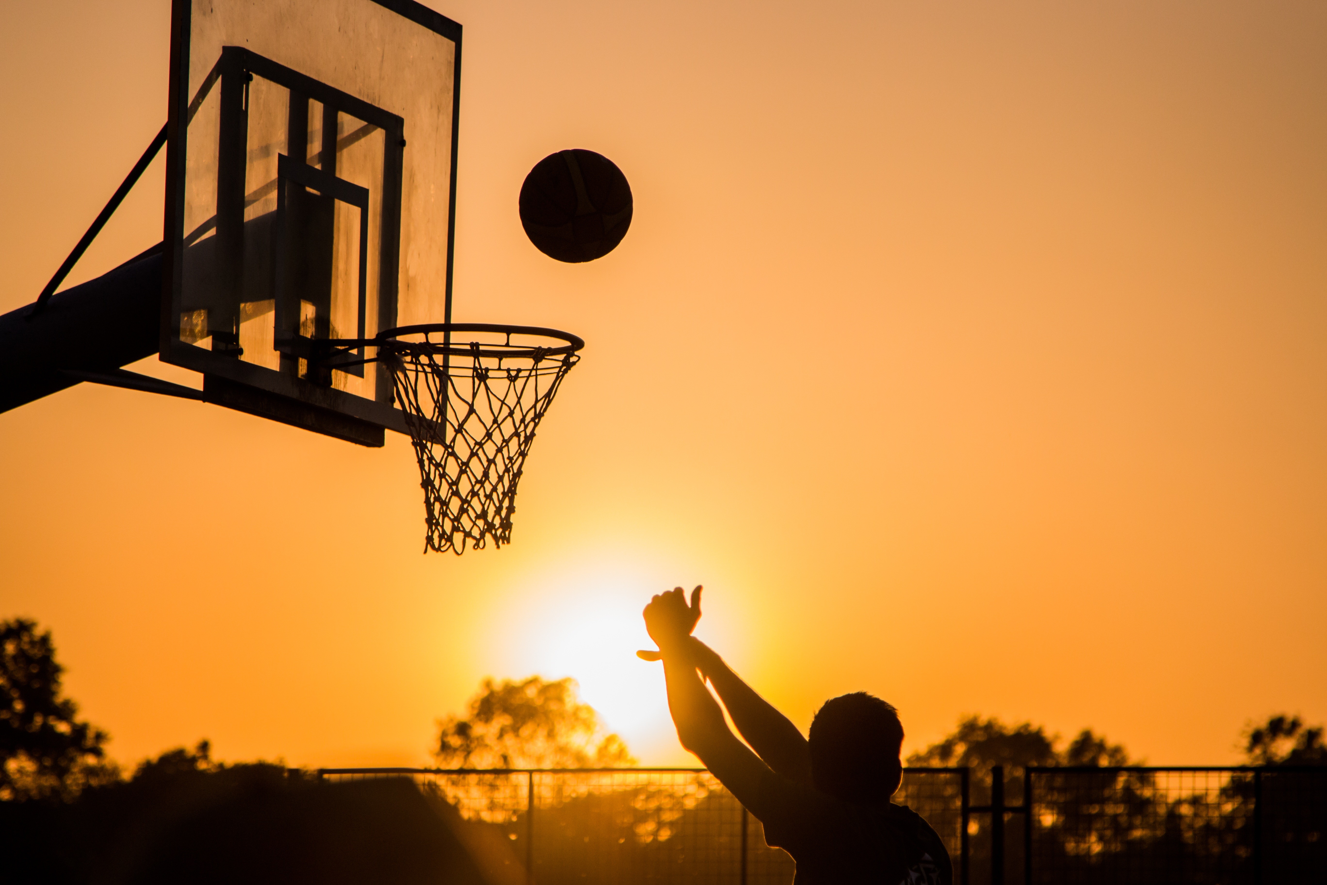 Man playing basketball in sunset