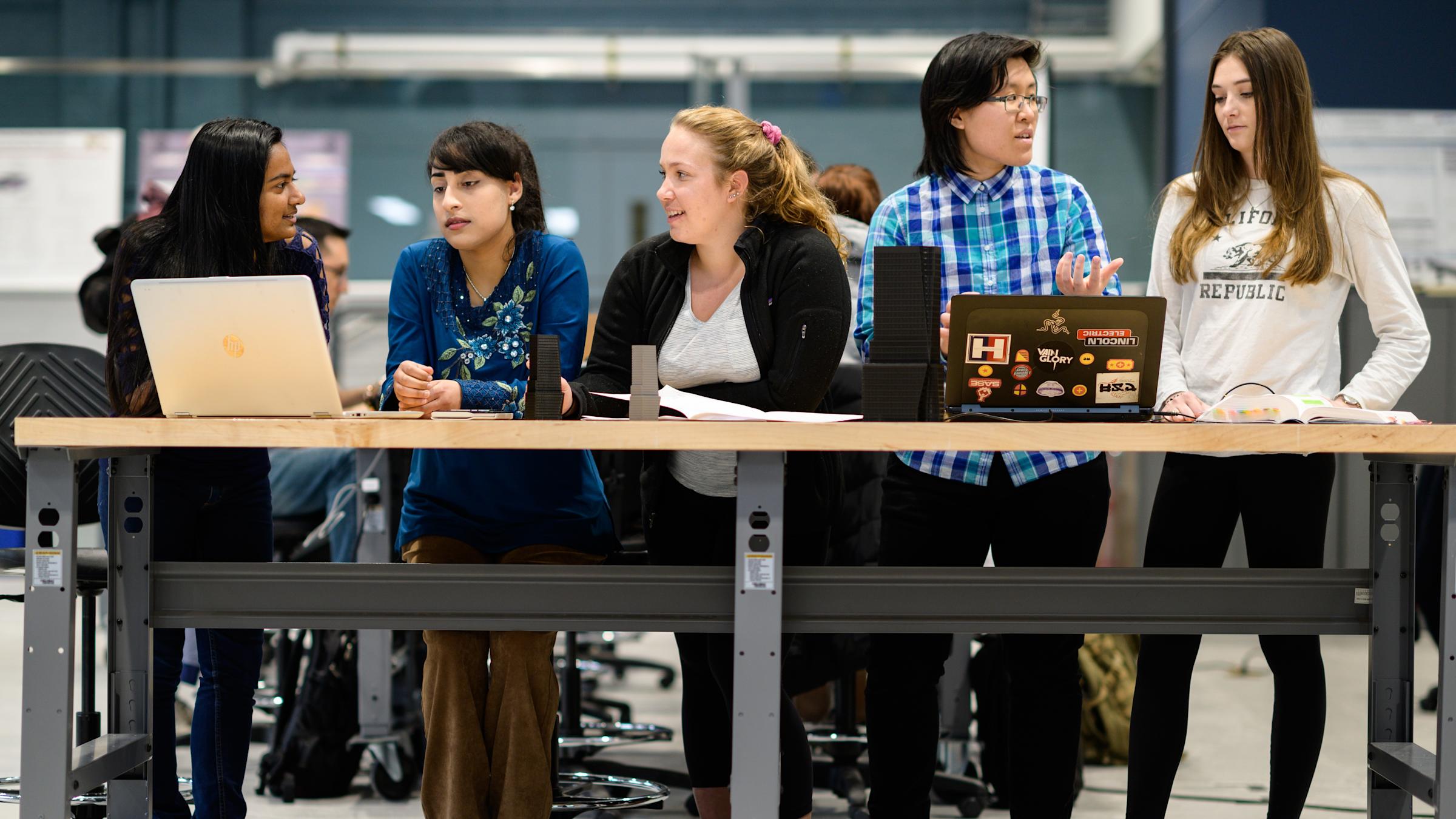5 Women standing around a table
