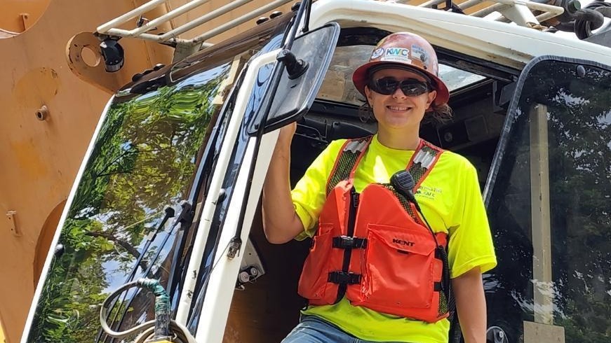 A civil engineering student posing on heavy equipment.