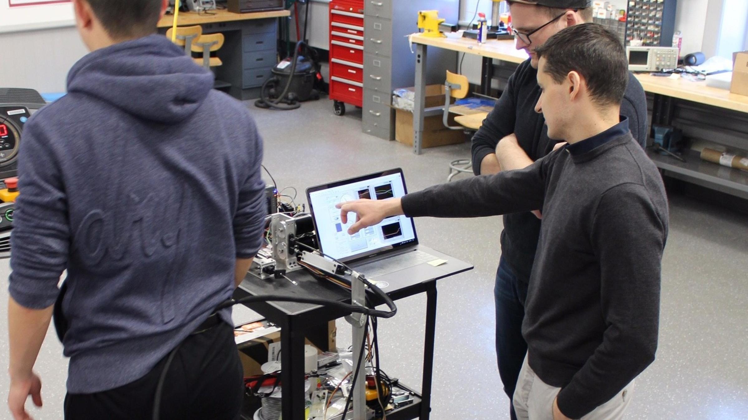 Two researchers examine a monitor with an image of brainwaves.