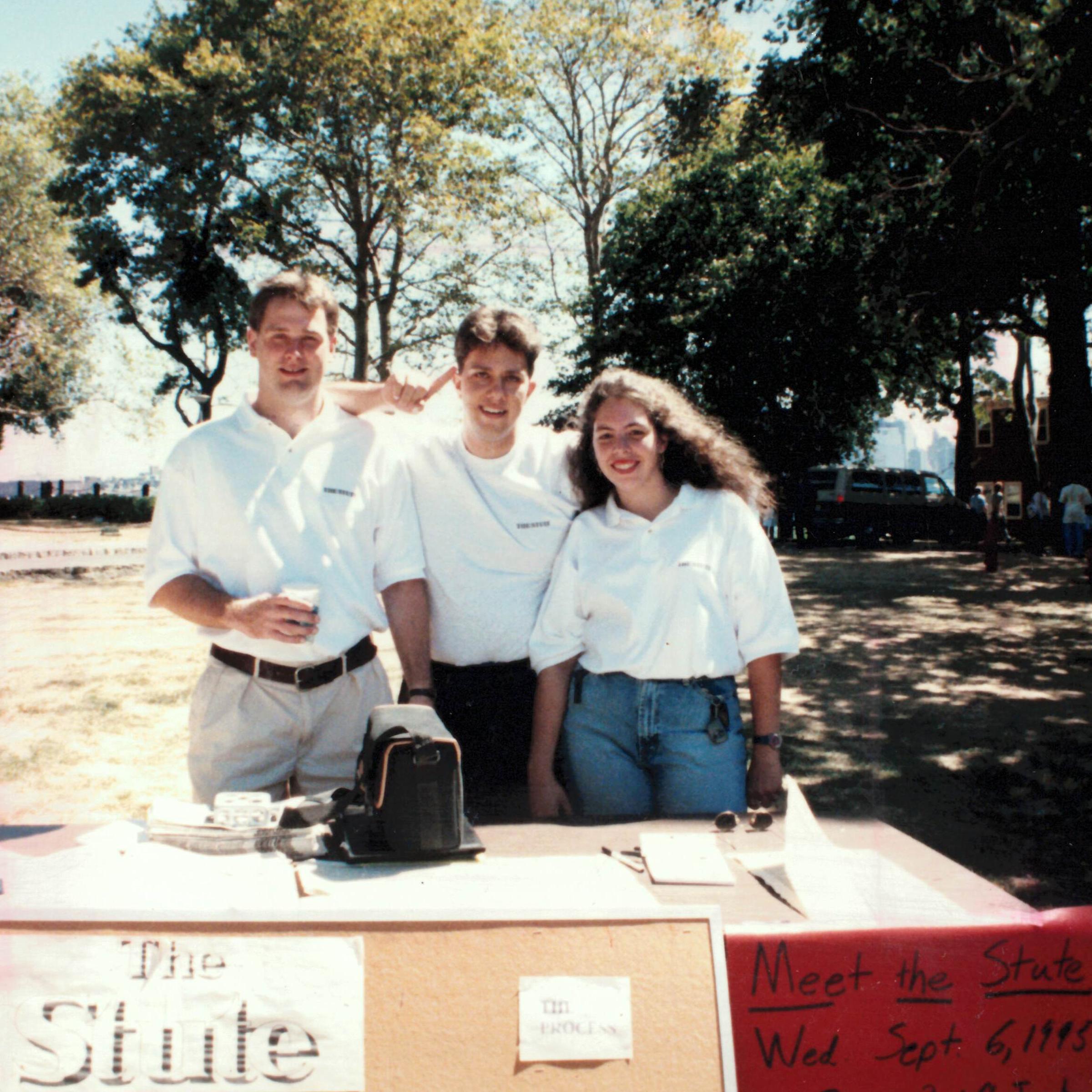 Three Stute representatives on campus behind a table for The Stute.