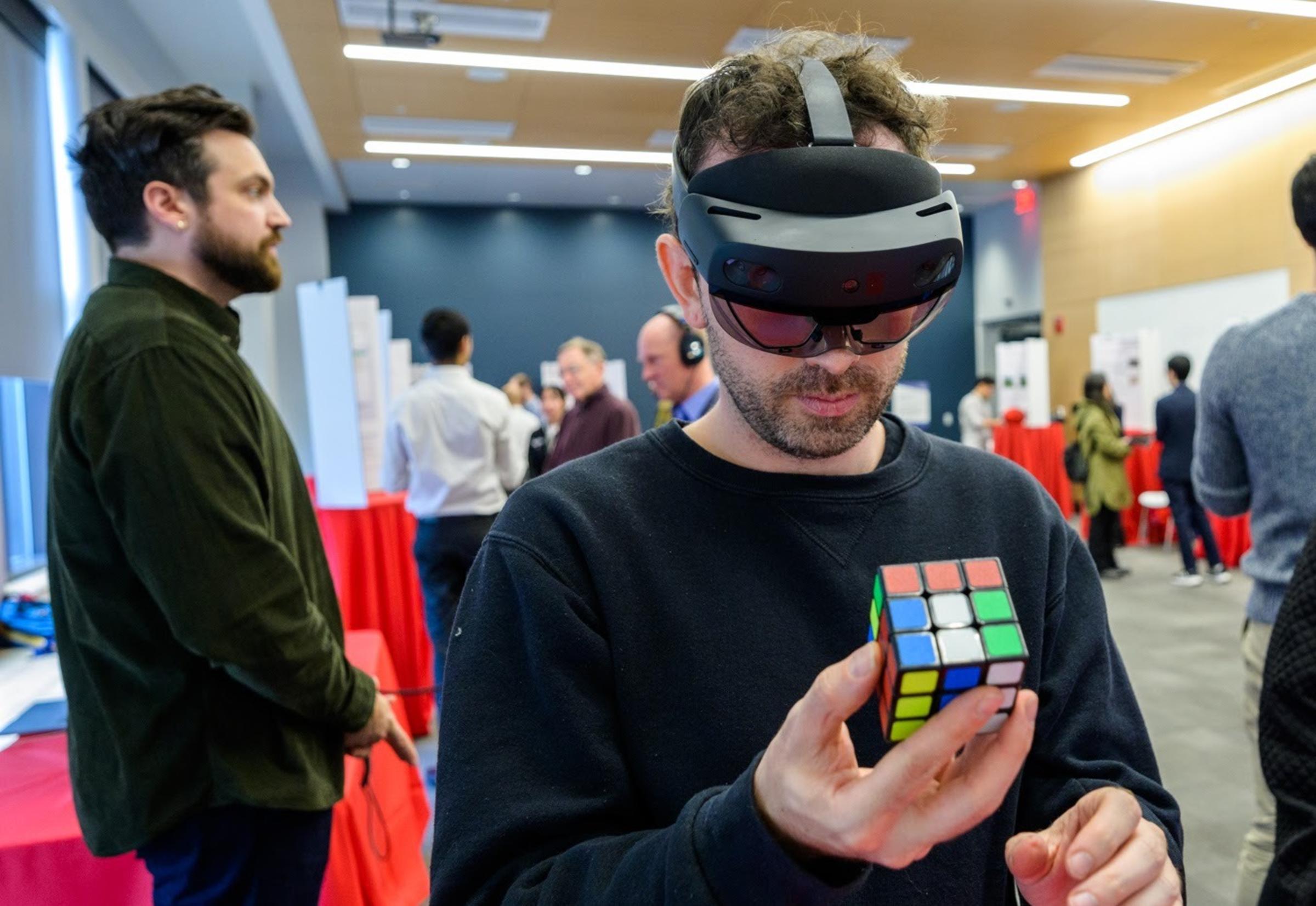 Attendee wearing VR goggles and holding Rubik's Cube at Stevens event