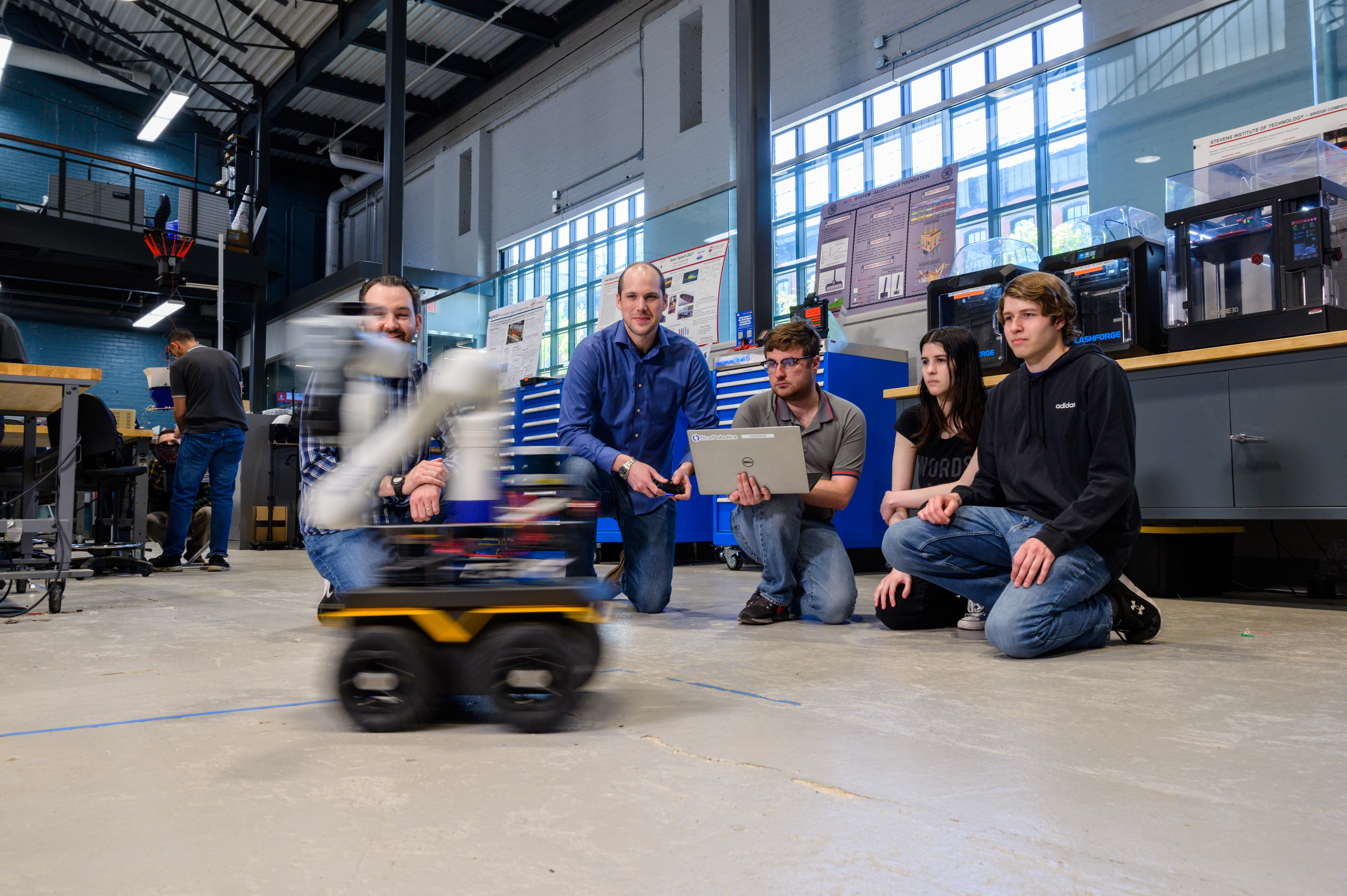 Students and professors gather on the floor to work on a robot 