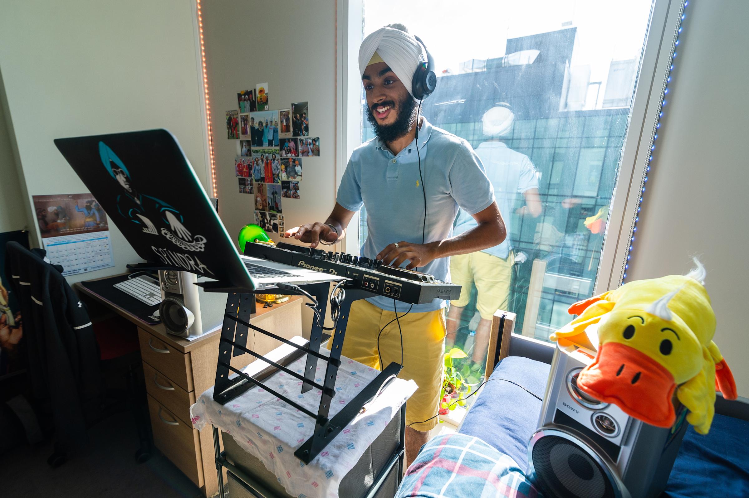 Student plays music on DJ machine while stuffed duck looks on.