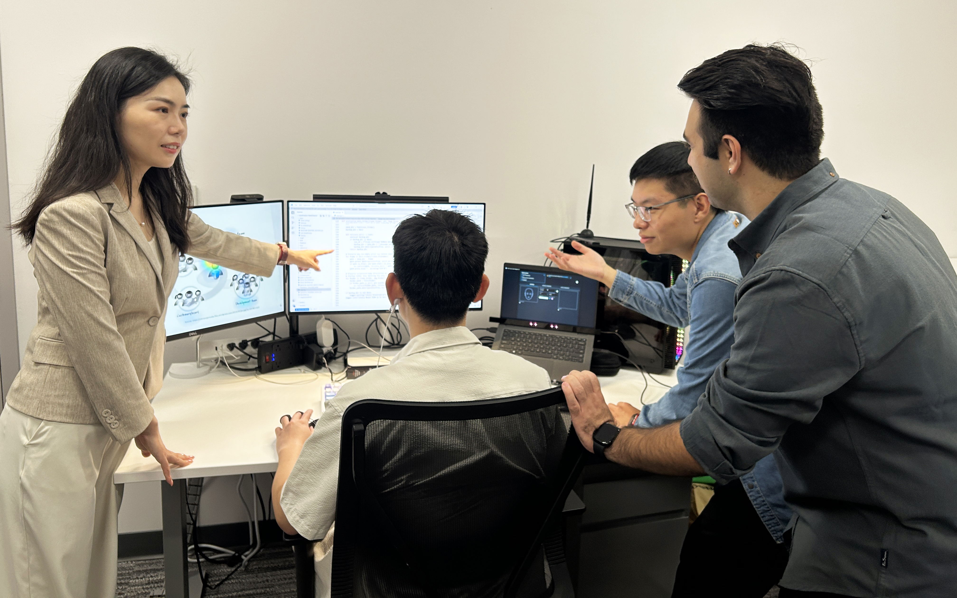 Ting Liao and a group of ph.d. students studying artificial intelligence research on the computer monitors in front of them.