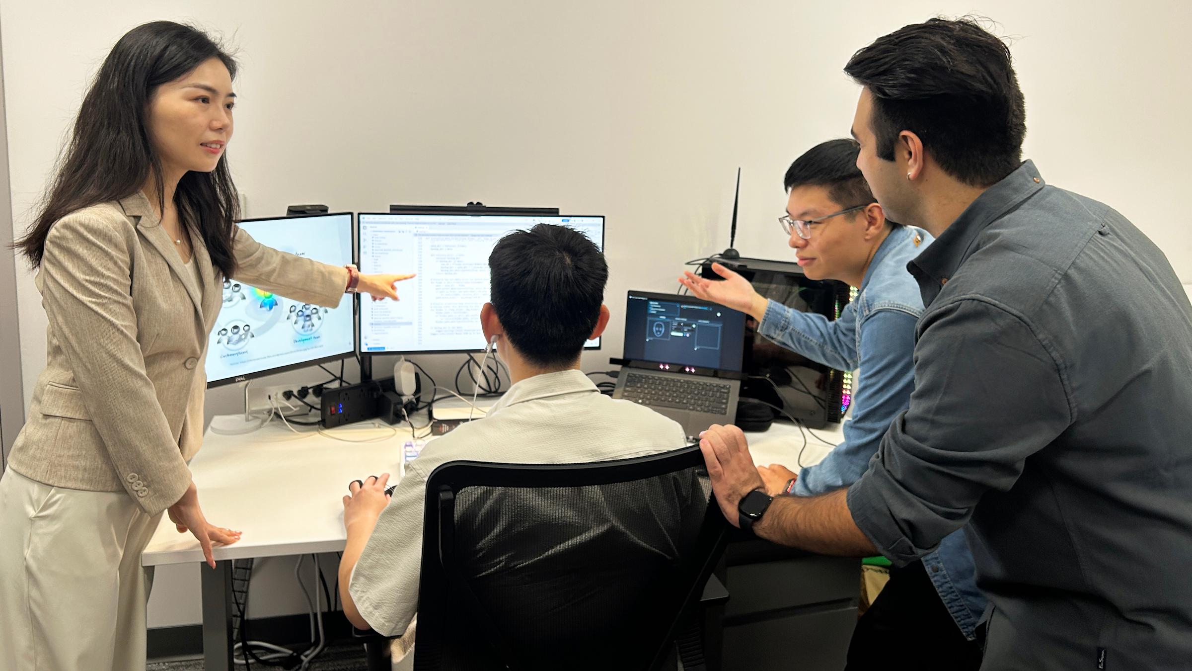Ting Liao and a group of ph.d. students studying artificial intelligence research on the computer monitors in front of them.