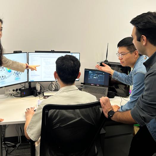 Ting Liao and a group of ph.d. students studying artificial intelligence research on the computer monitors in front of them.