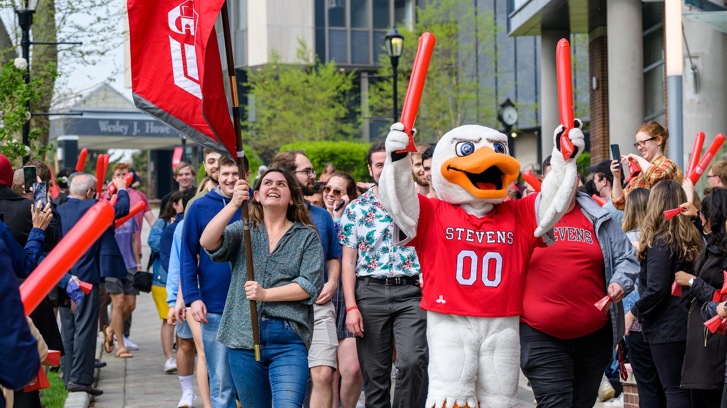Graduating students walk on Wittpenn Walk with Attila and cheering crowds
