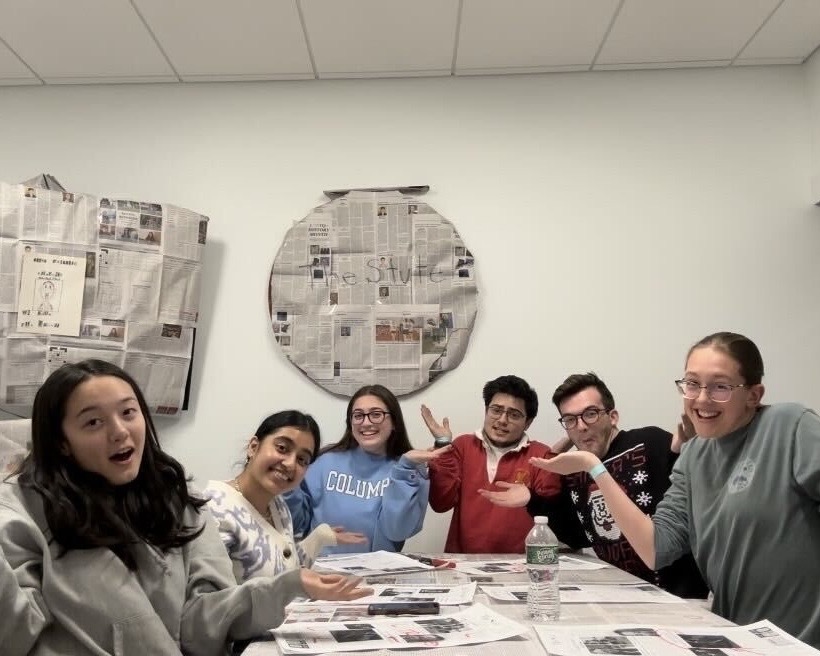 Stute students shrug at camera surrounded by newspapers