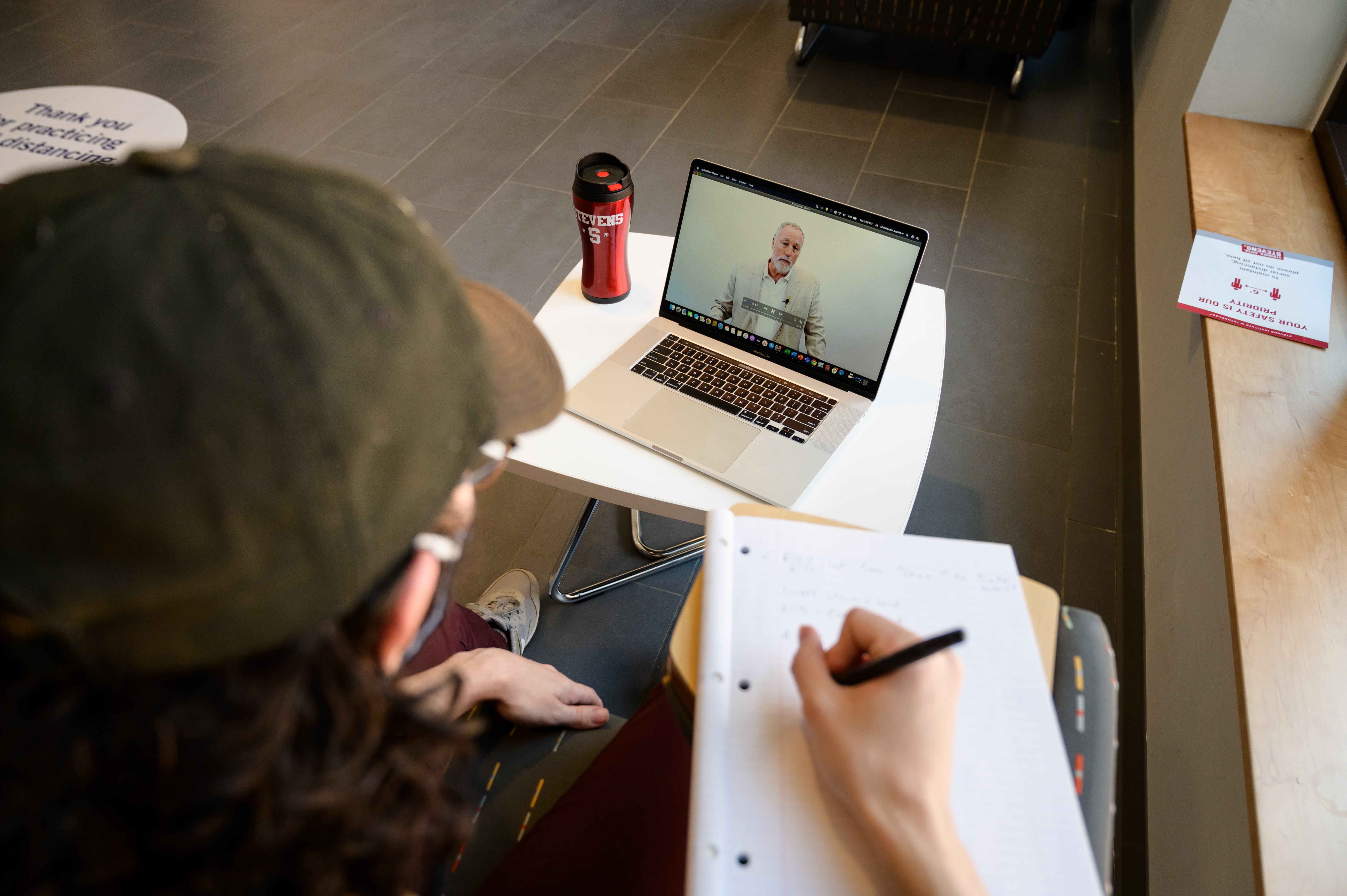 Student taking notes while watching an online lecture