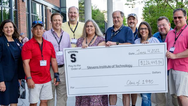Large check presentation with group of alumni