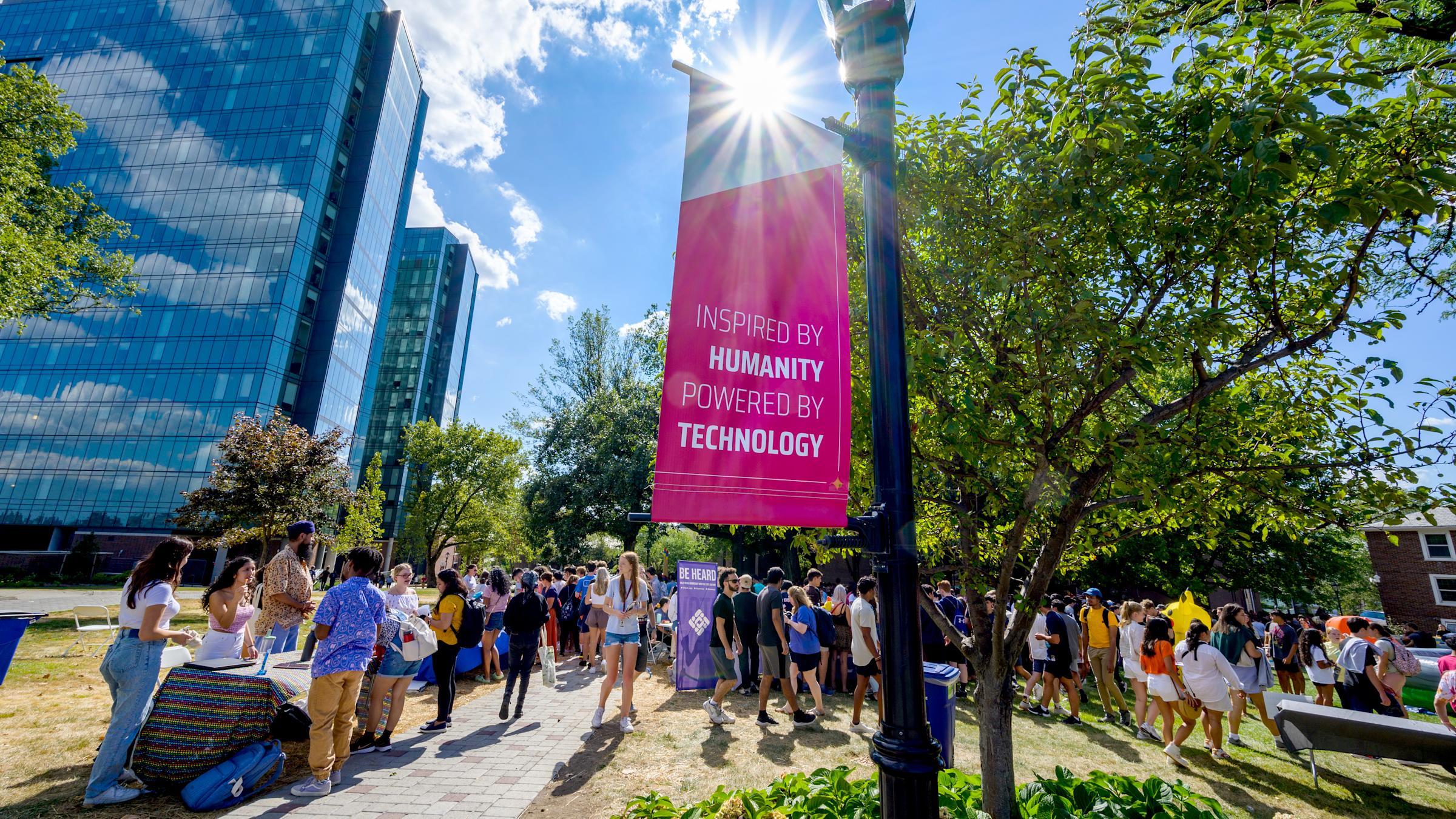 Event on Stevens campus with banner in foreground that reads "Inspired by Humanity, Powered by Technology"