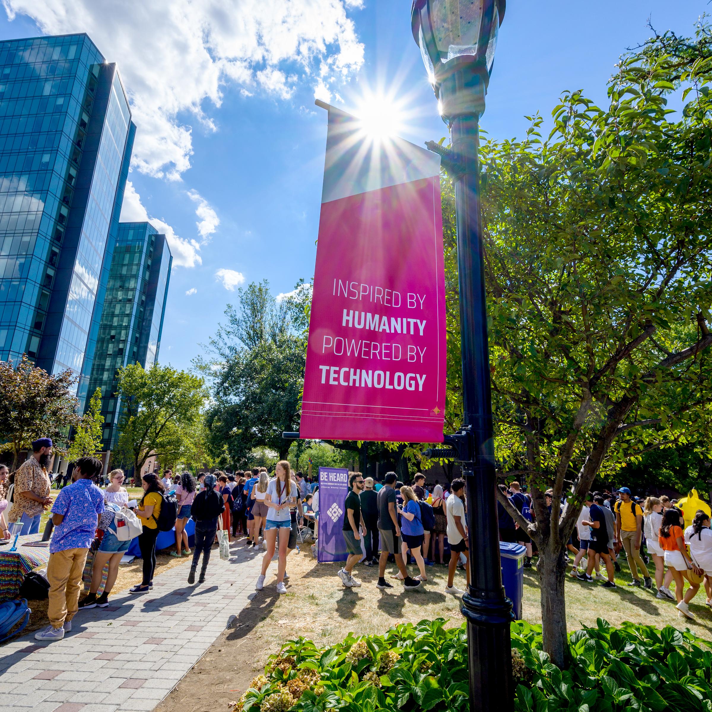 Event on Stevens campus with banner in foreground that reads "Inspired by Humanity, Powered by Technology"