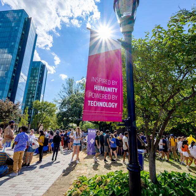 Event on Stevens campus with banner in foreground that reads "Inspired by Humanity, Powered by Technology"