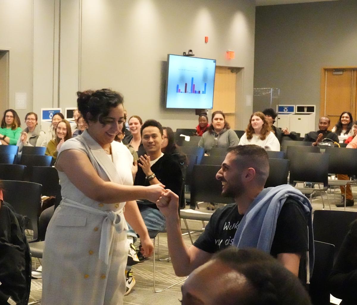Rana Ibrahim stands and gives a fist-bump to a student sitting in the audience.