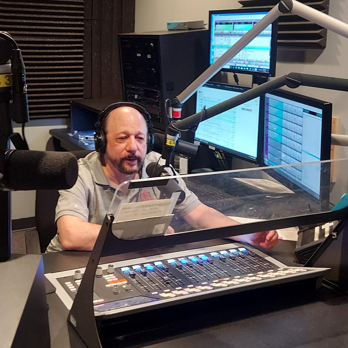 Paul Porzio ’77 sits at the radio station in Fairfax, Virginia speaking into the radio microphone