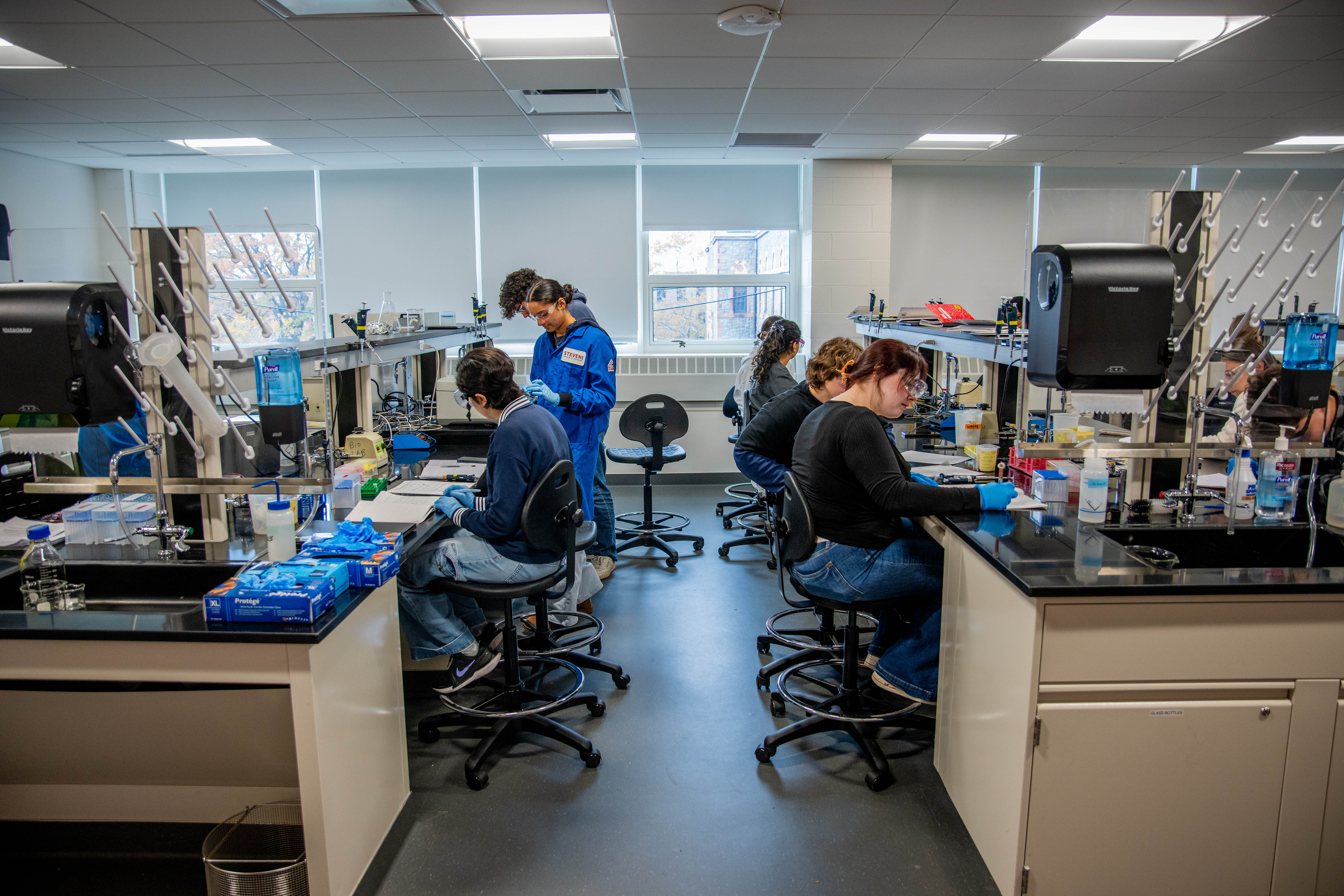 A mix of male and female students complete hands-on work in a lab setting.