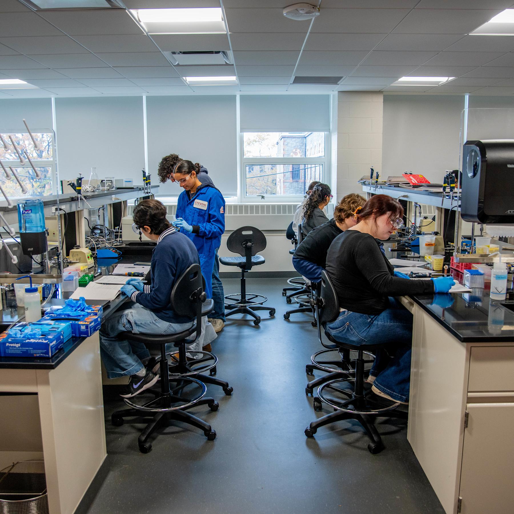 A mix of male and female students complete hands-on work in a lab setting.