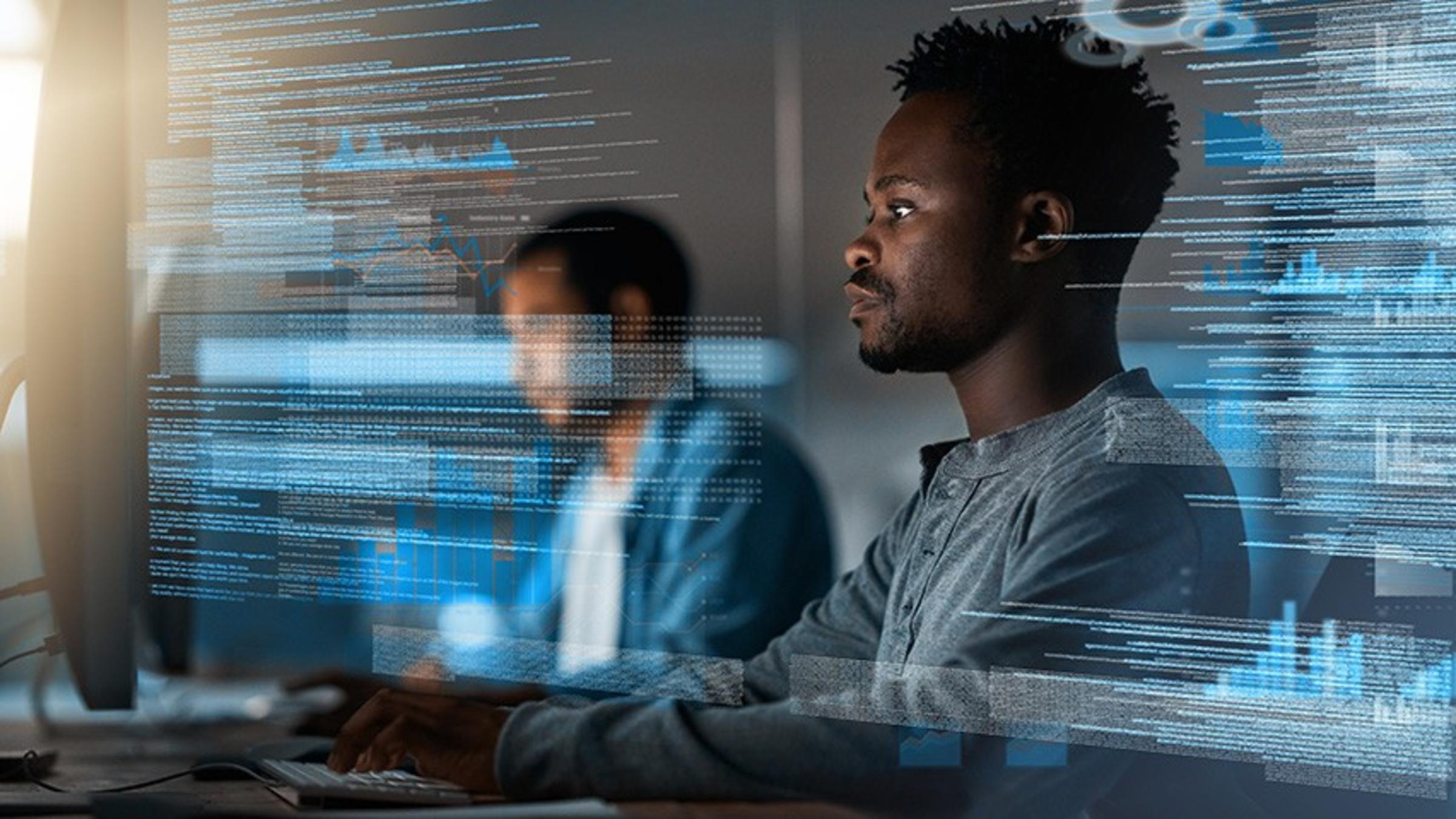 Two male students coding in a high-tech digital business lab.