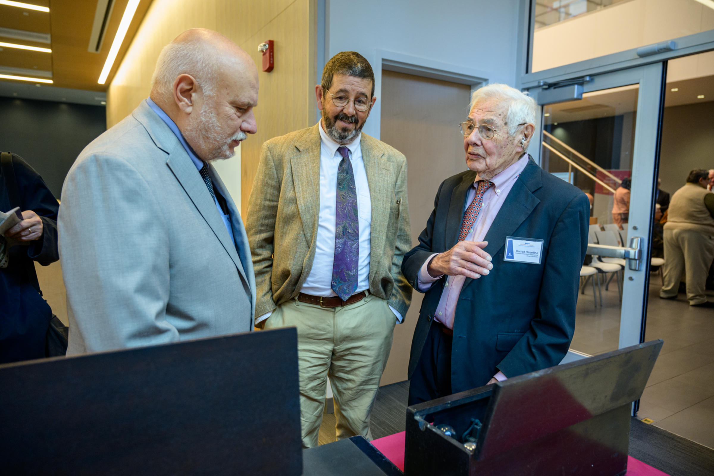 Three men chat in front of an antique radio. Left to right: Mike Molnar, Michael Hazeltine and Barrett Hazeltine.