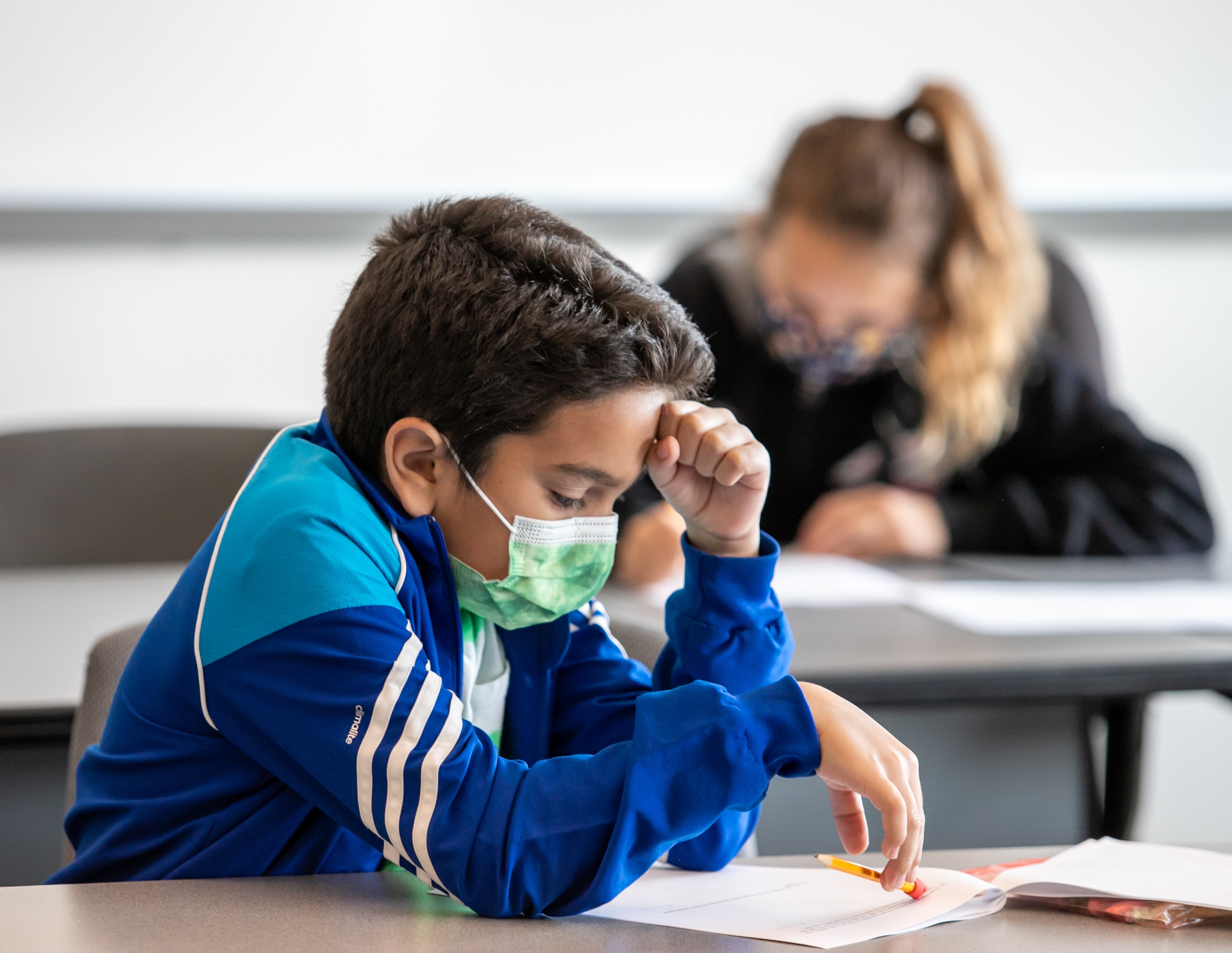 Math Olympiad participant reviewing test with fist on forehead