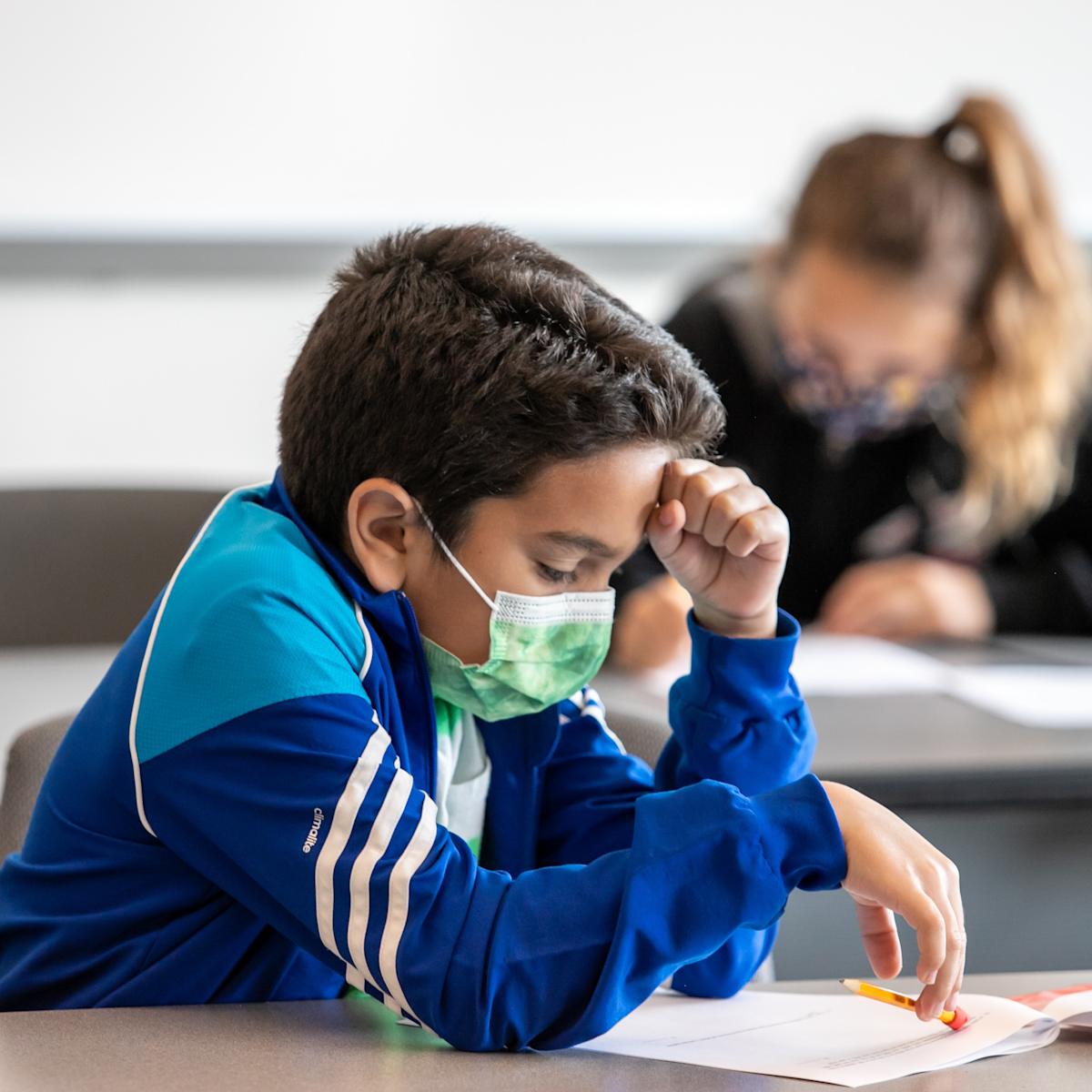 Math Olympiad participant reviewing test with fist on forehead