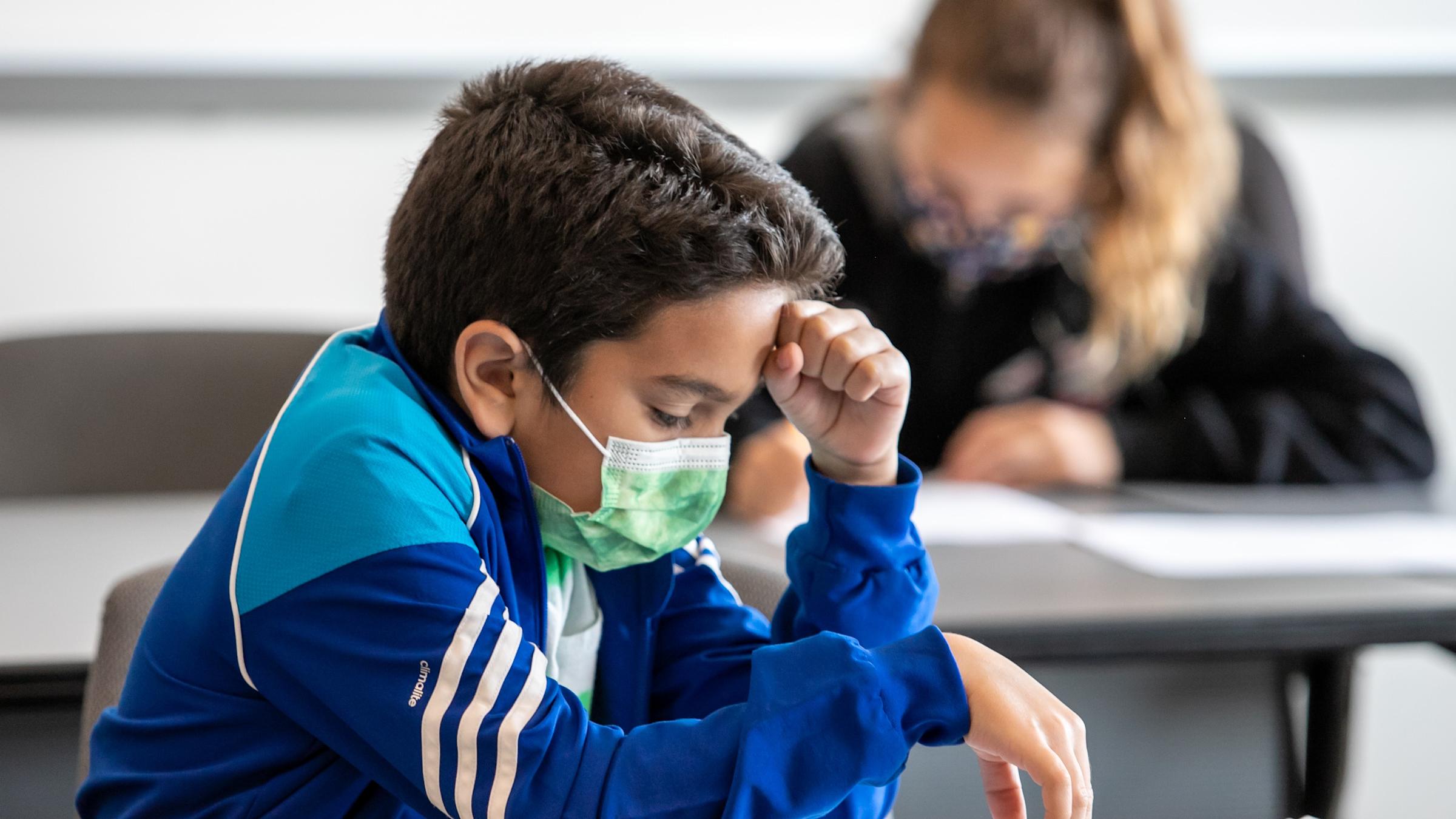Math Olympiad participant reviewing test with fist on forehead
