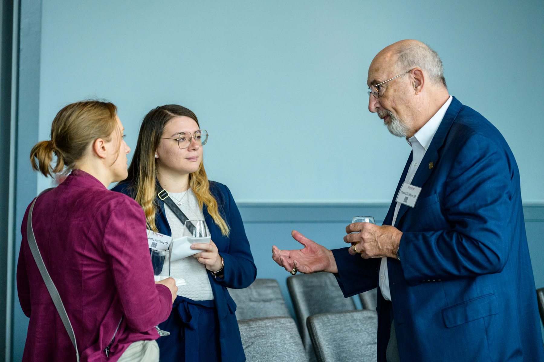 Three alumni gather to chat and network with each other at an event