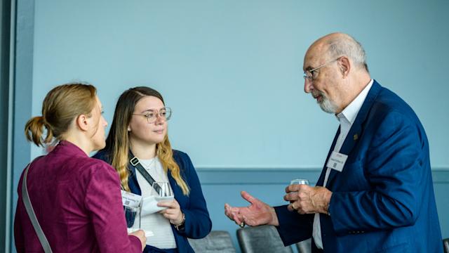 Three alumni gather to chat and network with each other at an event