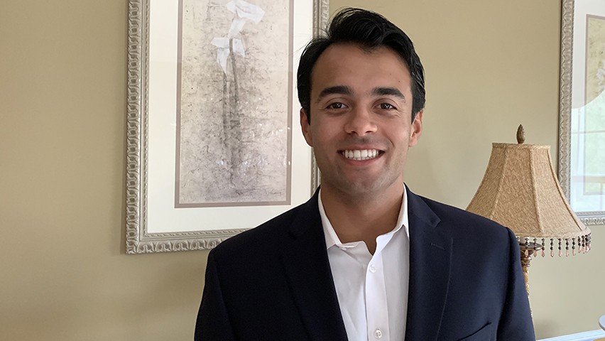 Vince Falvo poses for the camera in his home, wearing a dark jacket and white dress shirt.