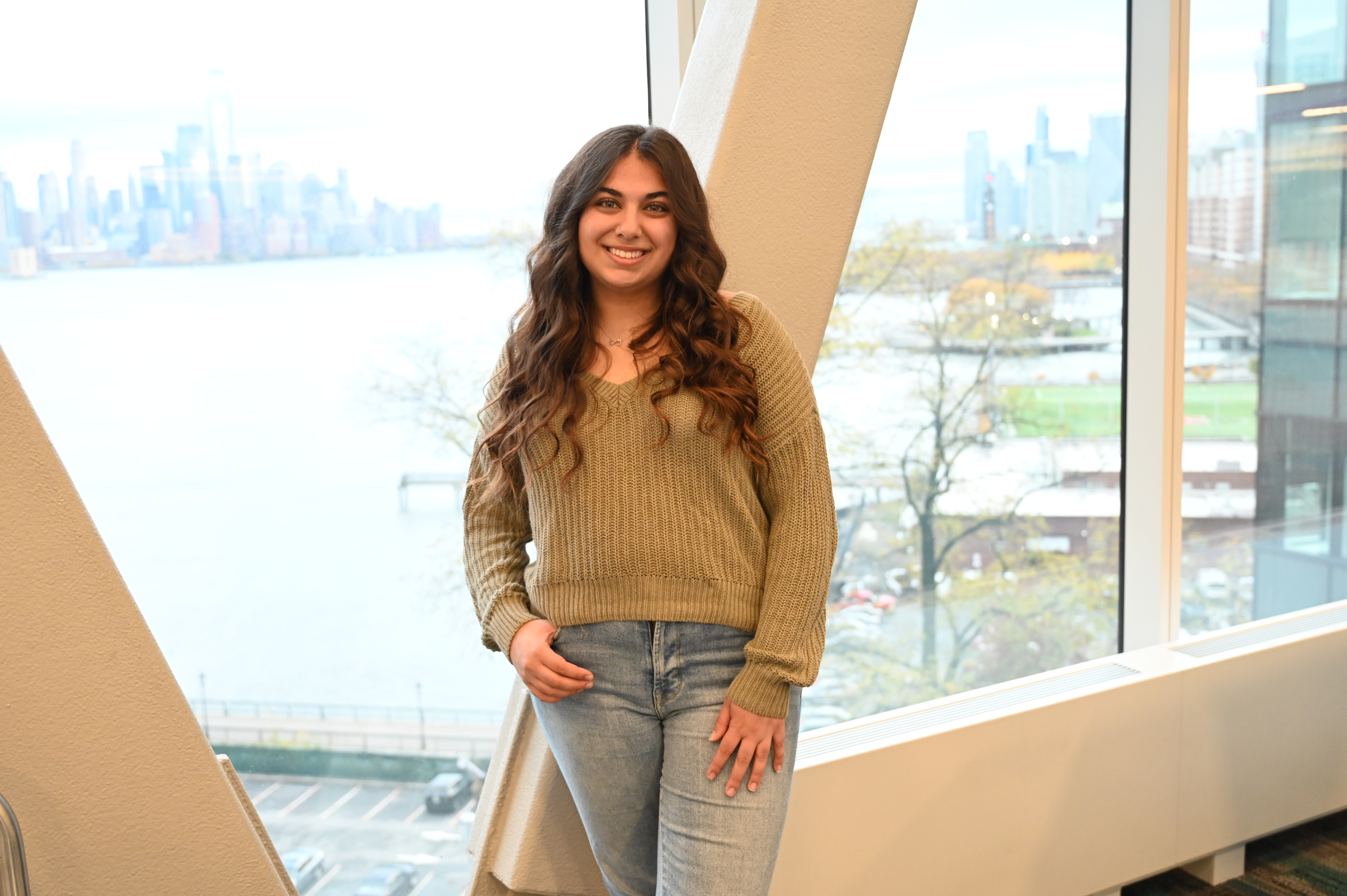 A woman stands in front of a window.