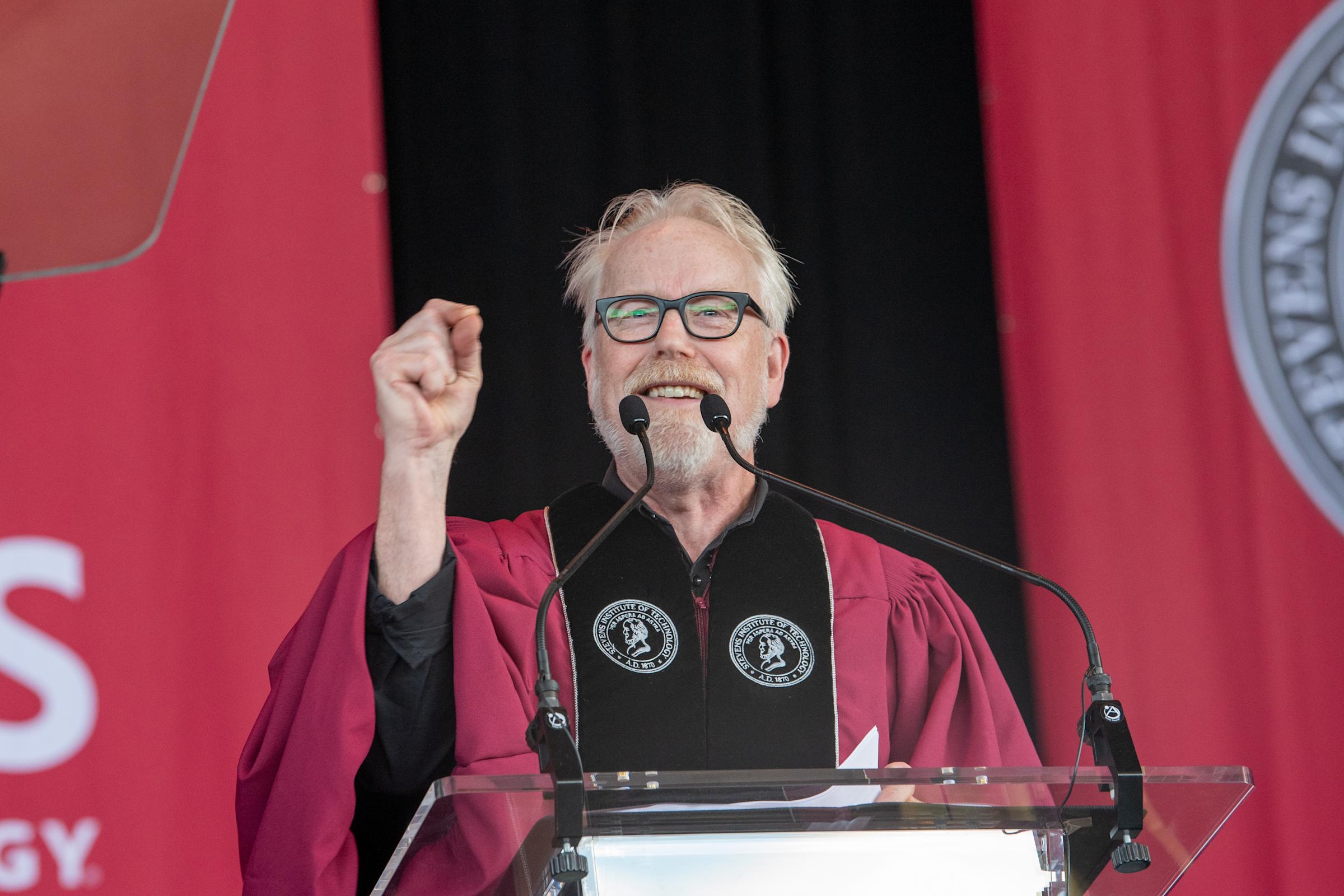 A man speaks at a podium at a graduation ceremony.