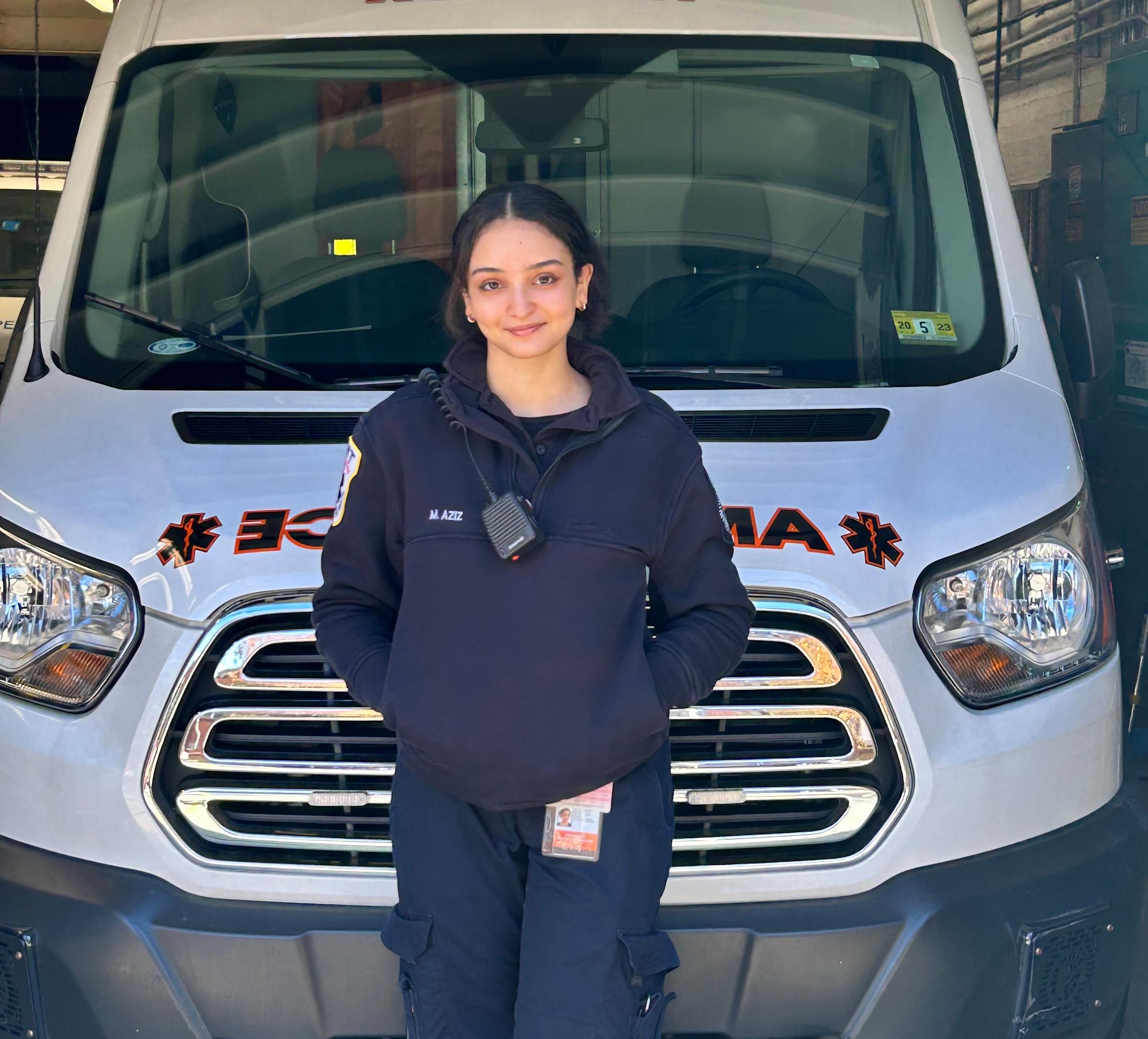 Malak Aziz ‘24 stands in front of an ambulance, dressed in her EMT uniform