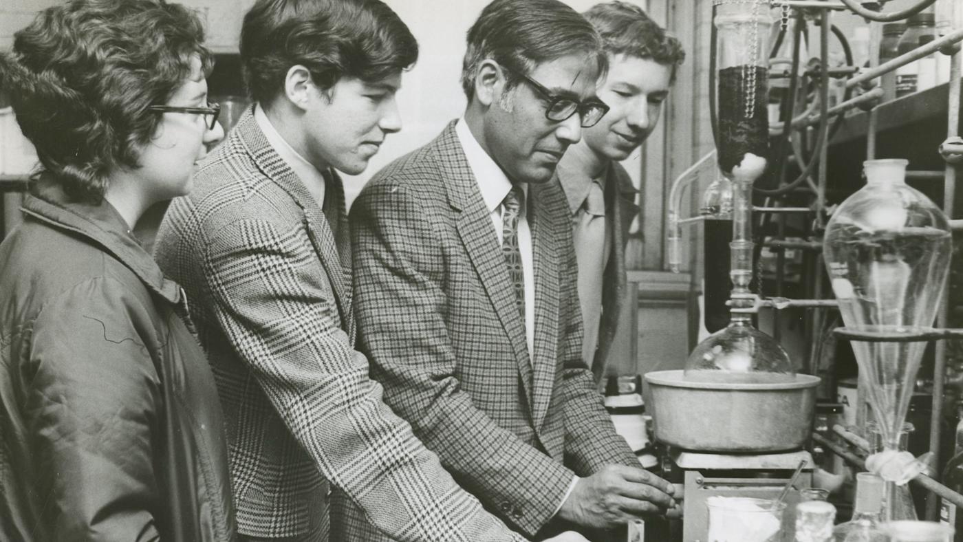 Dr. Ajay Bose works in a lab with three students in a vintage photo.