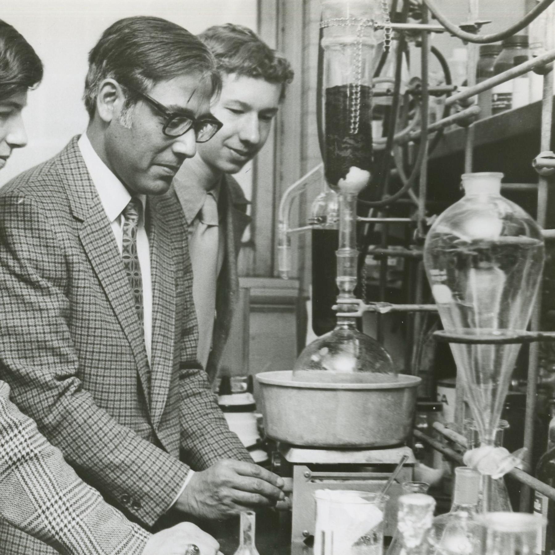 Dr. Ajay Bose works in a lab with three students in a vintage photo.