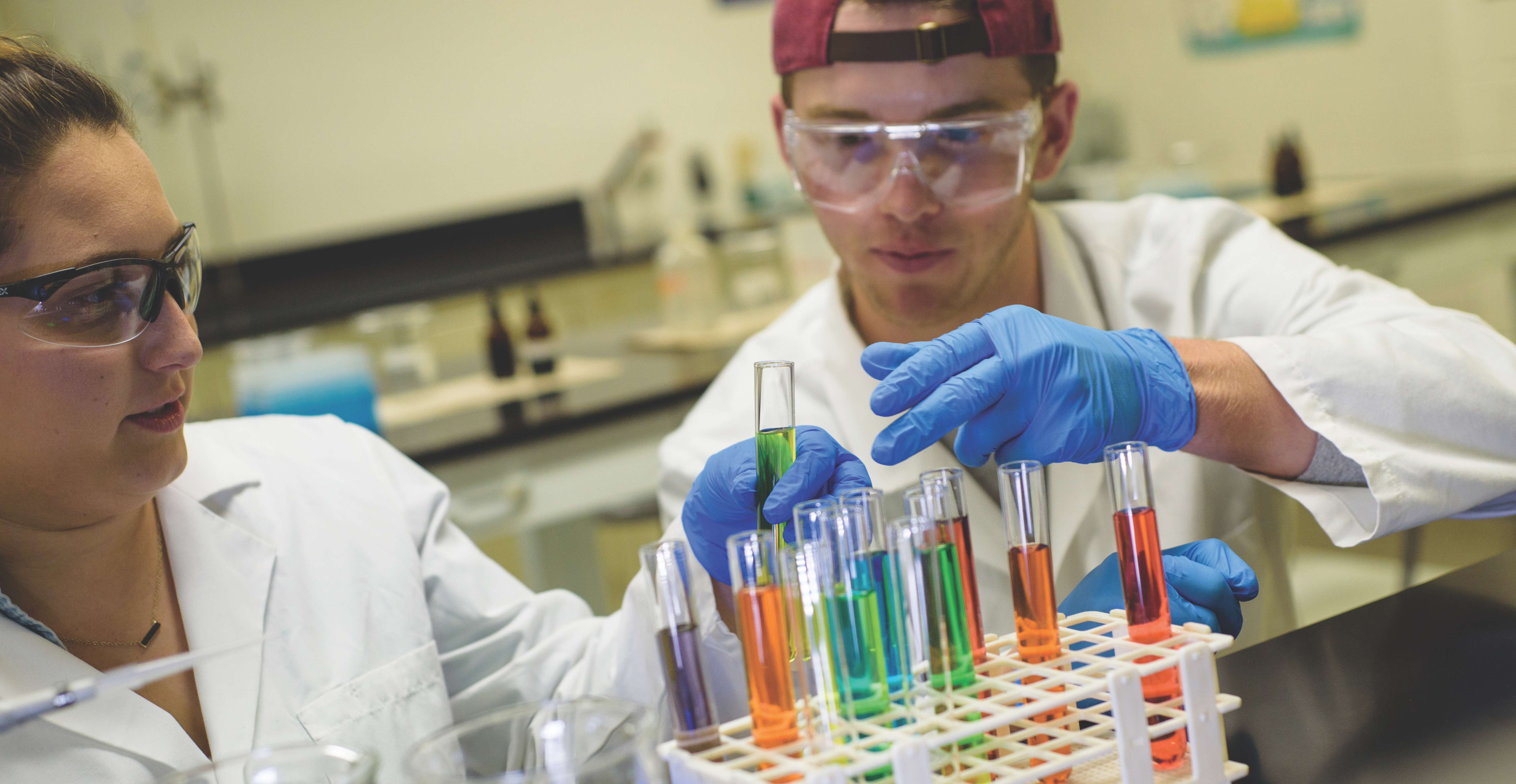 two students looking at colorful test tubes in a laboratory