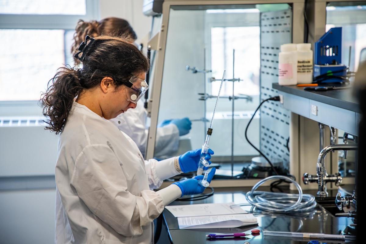 A photograph of a student researcher standing at her work station in the newly renovated organic chemistry lab conducting an experiment.