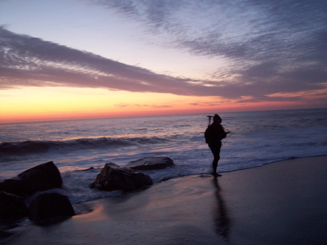 research student walking on the beach at sunset