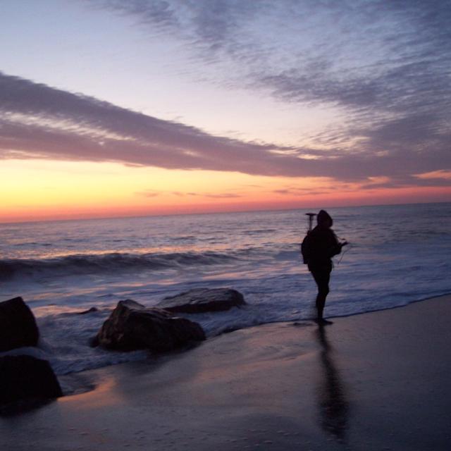 research student walking on the beach at sunset